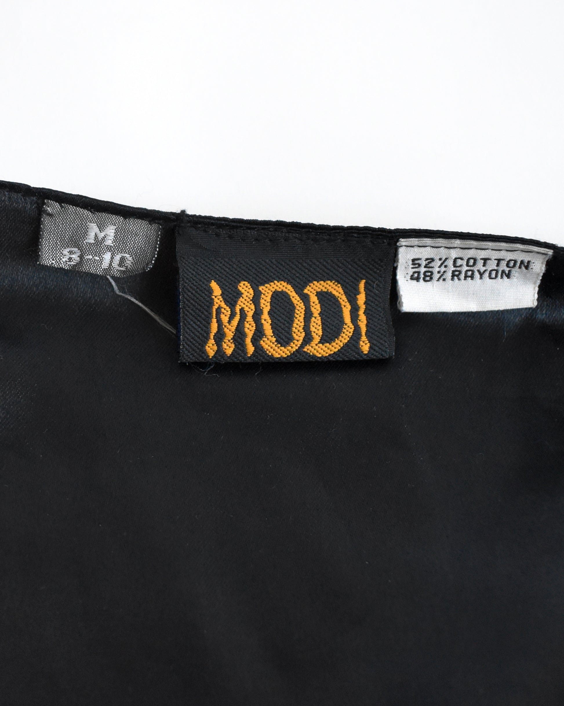 close up of the 'MODI' label and size tag on a white background