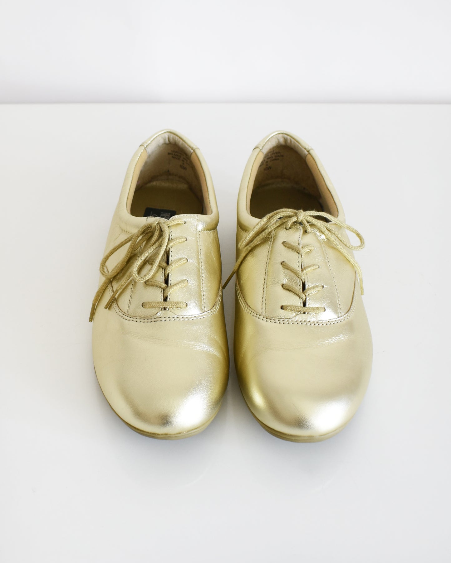 A pair of vintage metallic gold lace-up shoes, shown from both side and top-down angles on a clean white background.