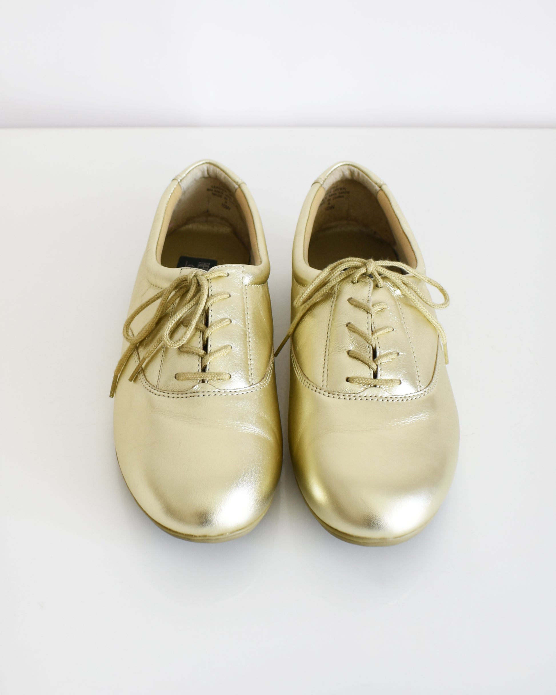 A pair of vintage metallic gold lace-up shoes, shown from both side and top-down angles on a clean white background.
