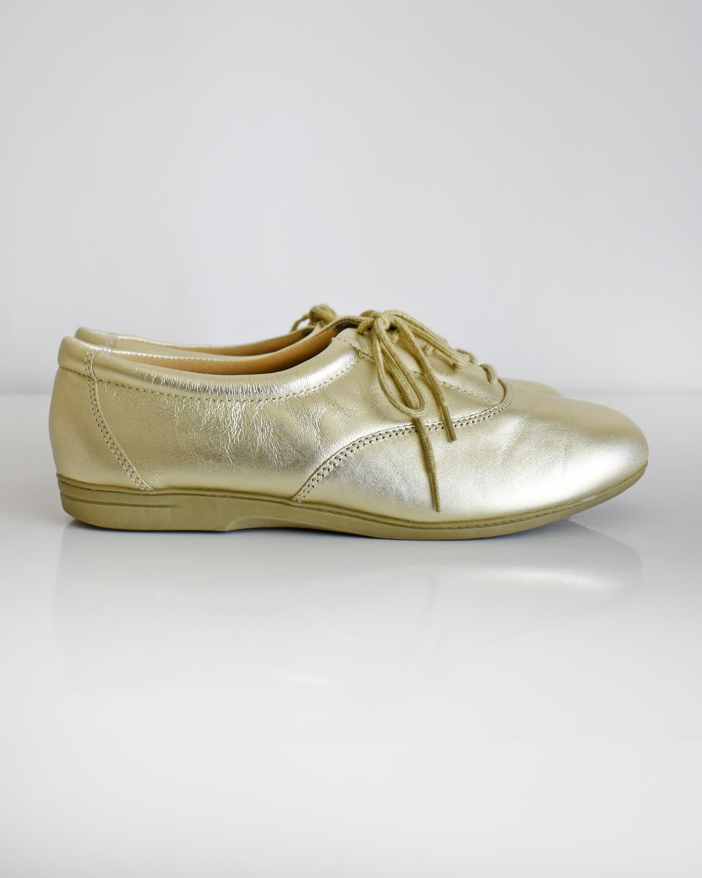 A pair of vintage metallic gold lace-up shoes, shown from both side and top-down angles on a clean white background.