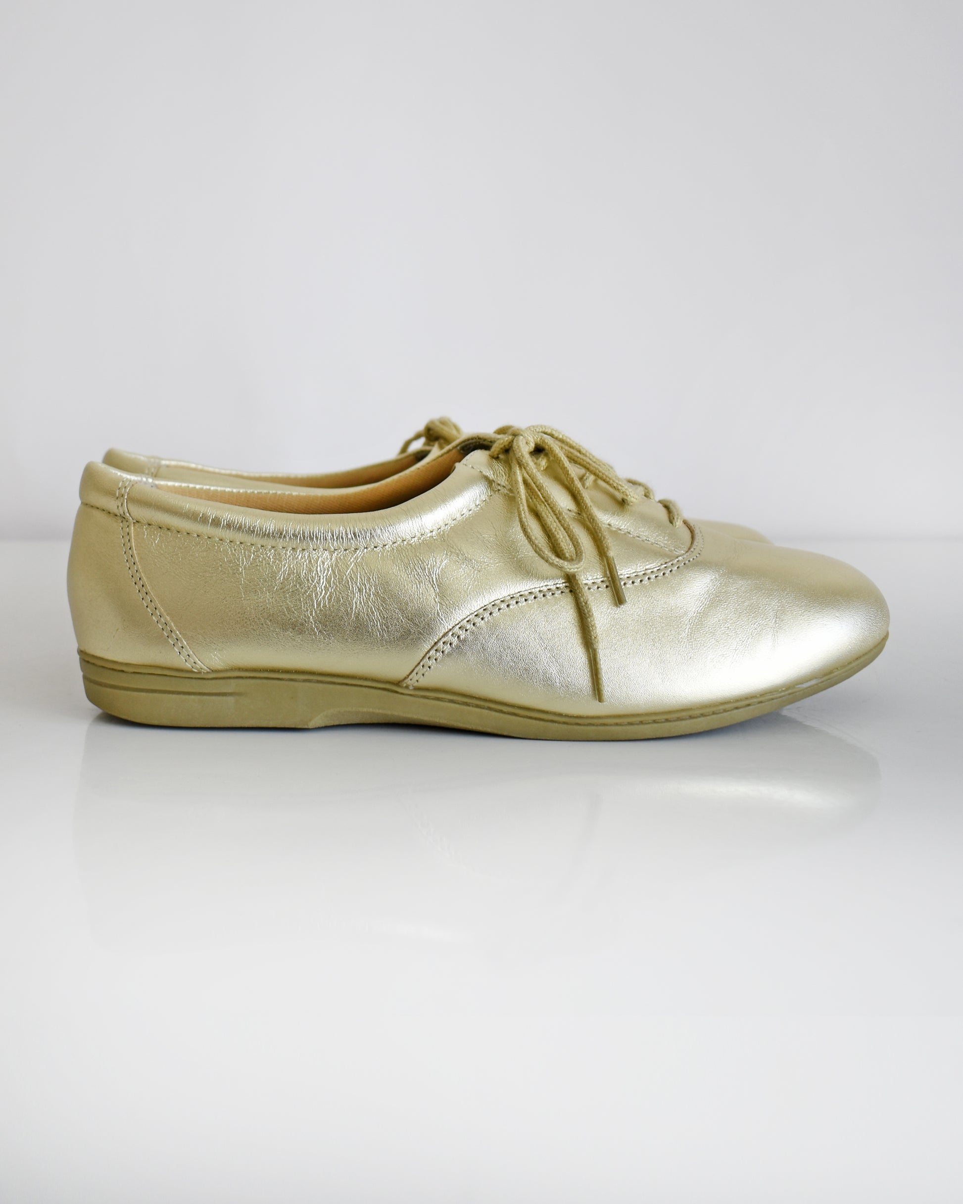 A pair of vintage metallic gold lace-up shoes, shown from both side and top-down angles on a clean white background.
