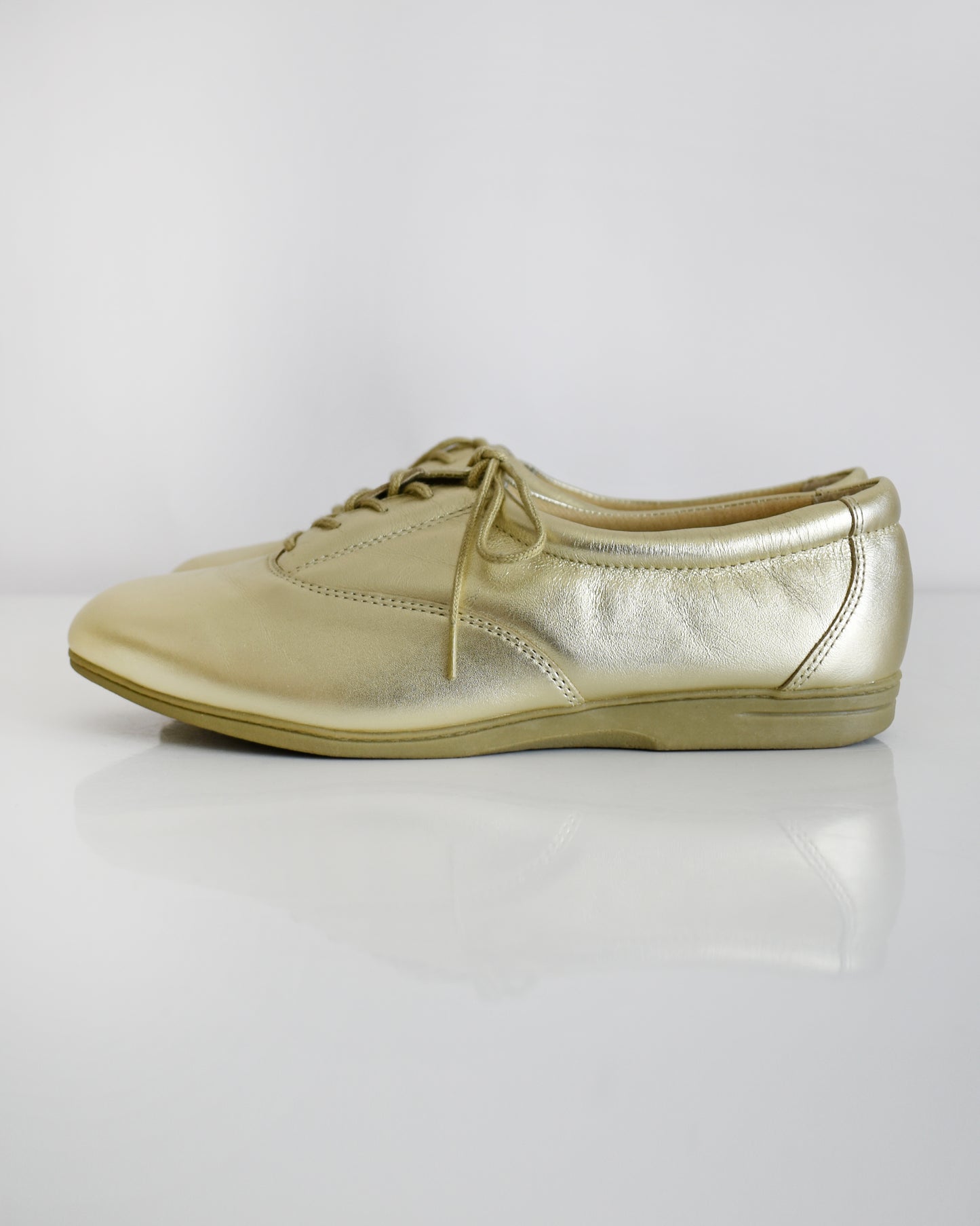 A pair of vintage metallic gold lace-up shoes, shown from both side and top-down angles on a clean white background.