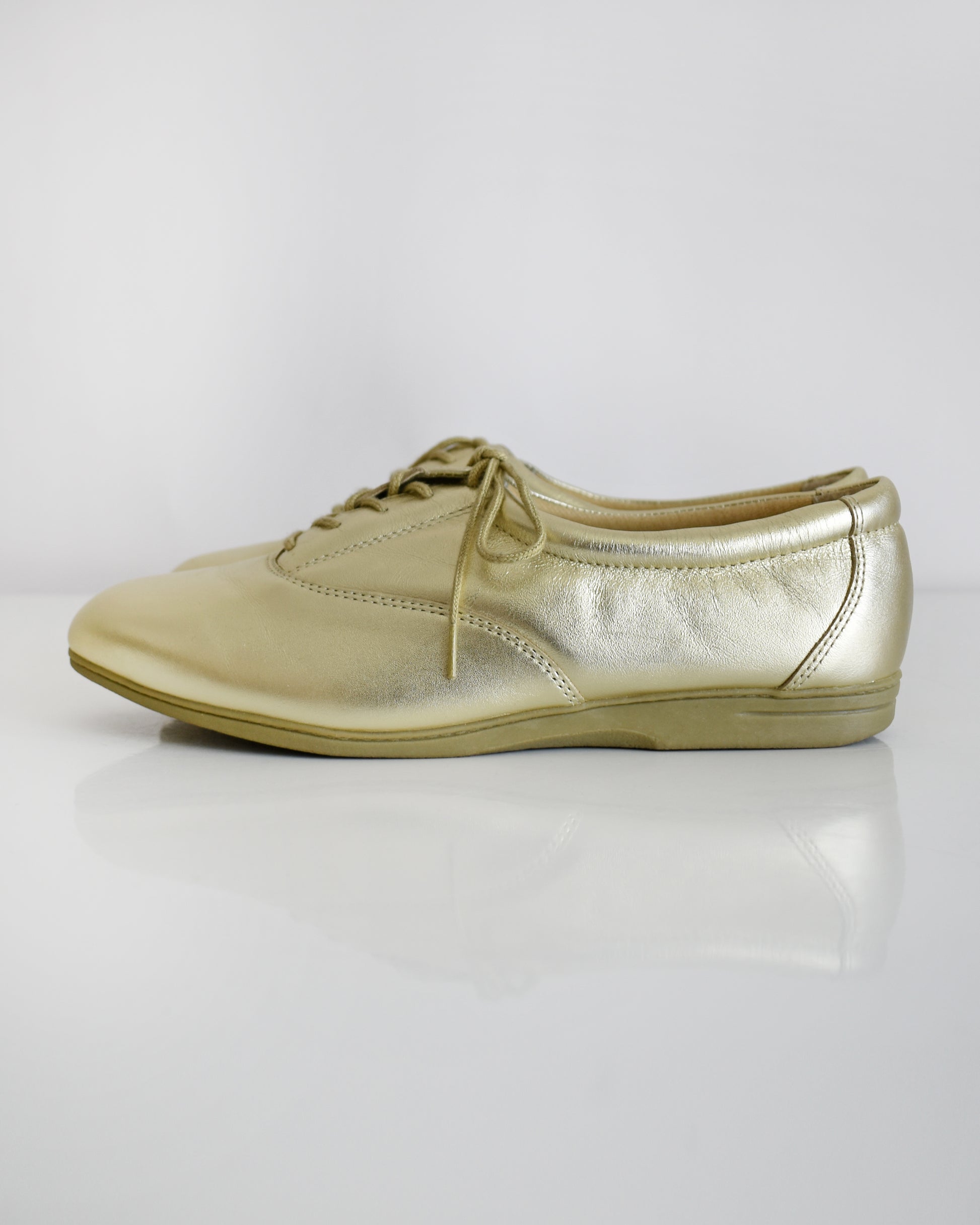 A pair of vintage metallic gold lace-up shoes, shown from both side and top-down angles on a clean white background.