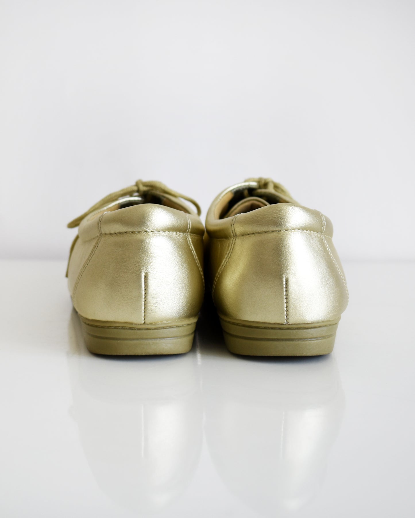 back view of a pair of vintage metallic gold lace-up shoes, shown from both side and top-down angles on a clean white background.