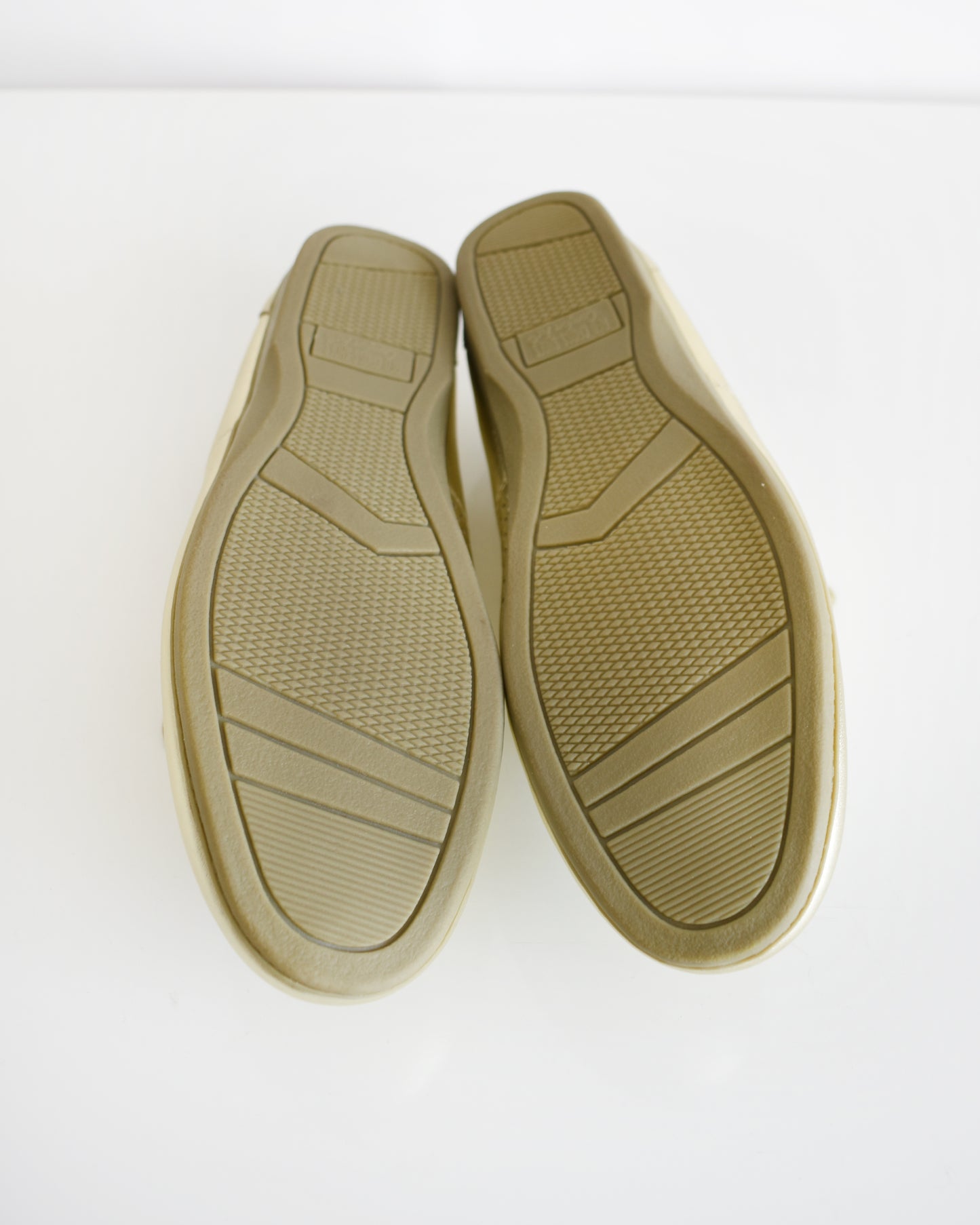 A pair of tan rubber shoe soles viewed from above on a plain white background.