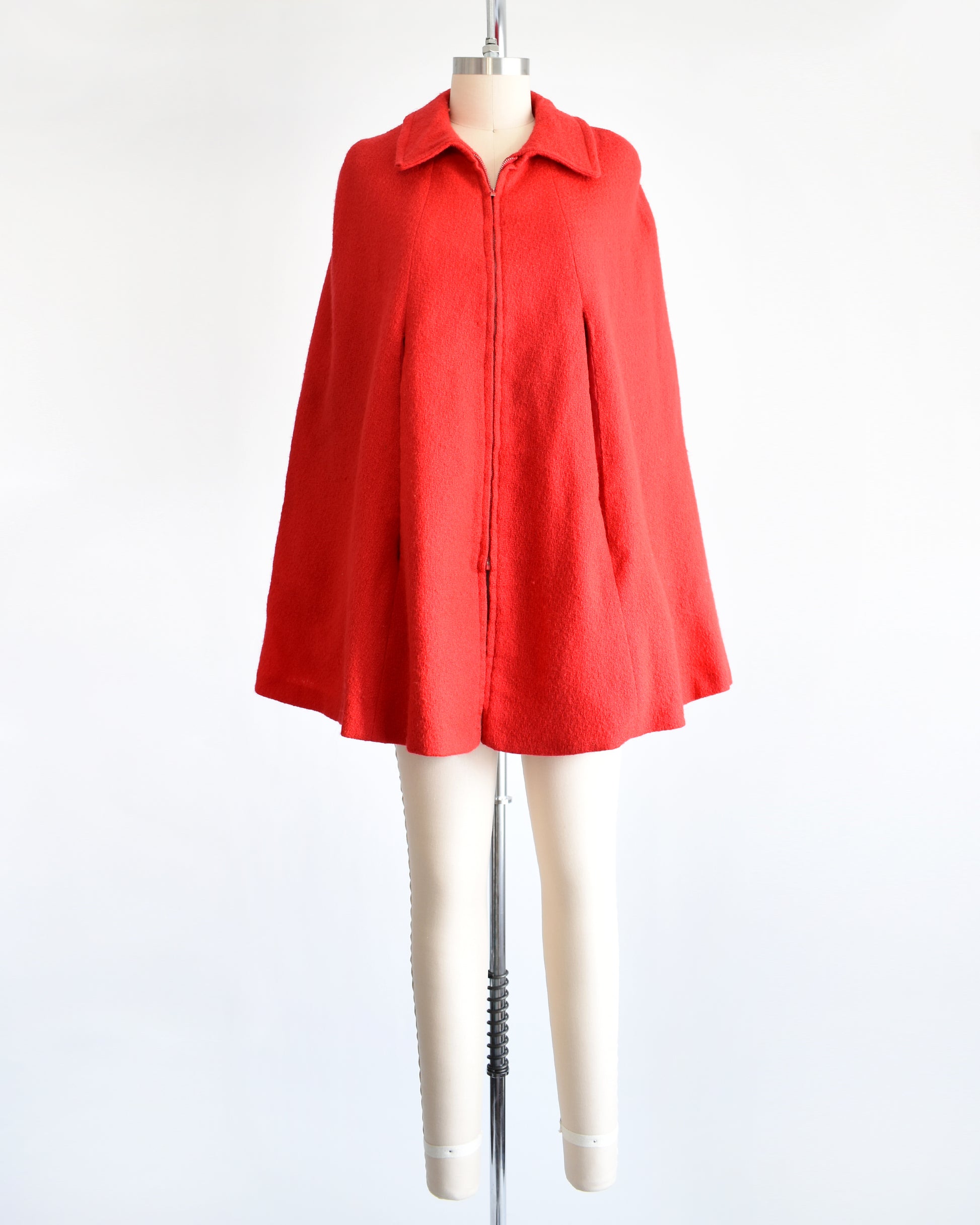 a vintage 1960s red cape with zip up front, front arm slits, and collared neckline.