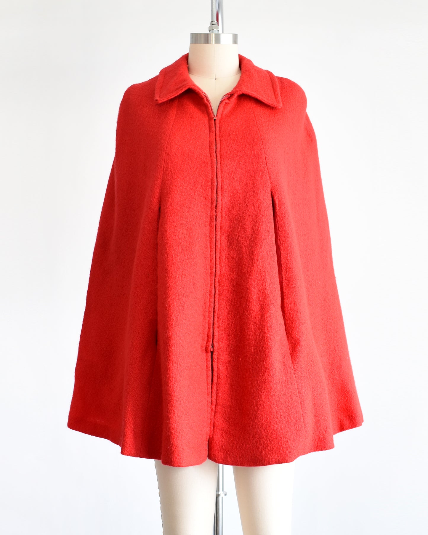 a vintage 1960s red cape with zip up front, front arm slits, and collared neckline.