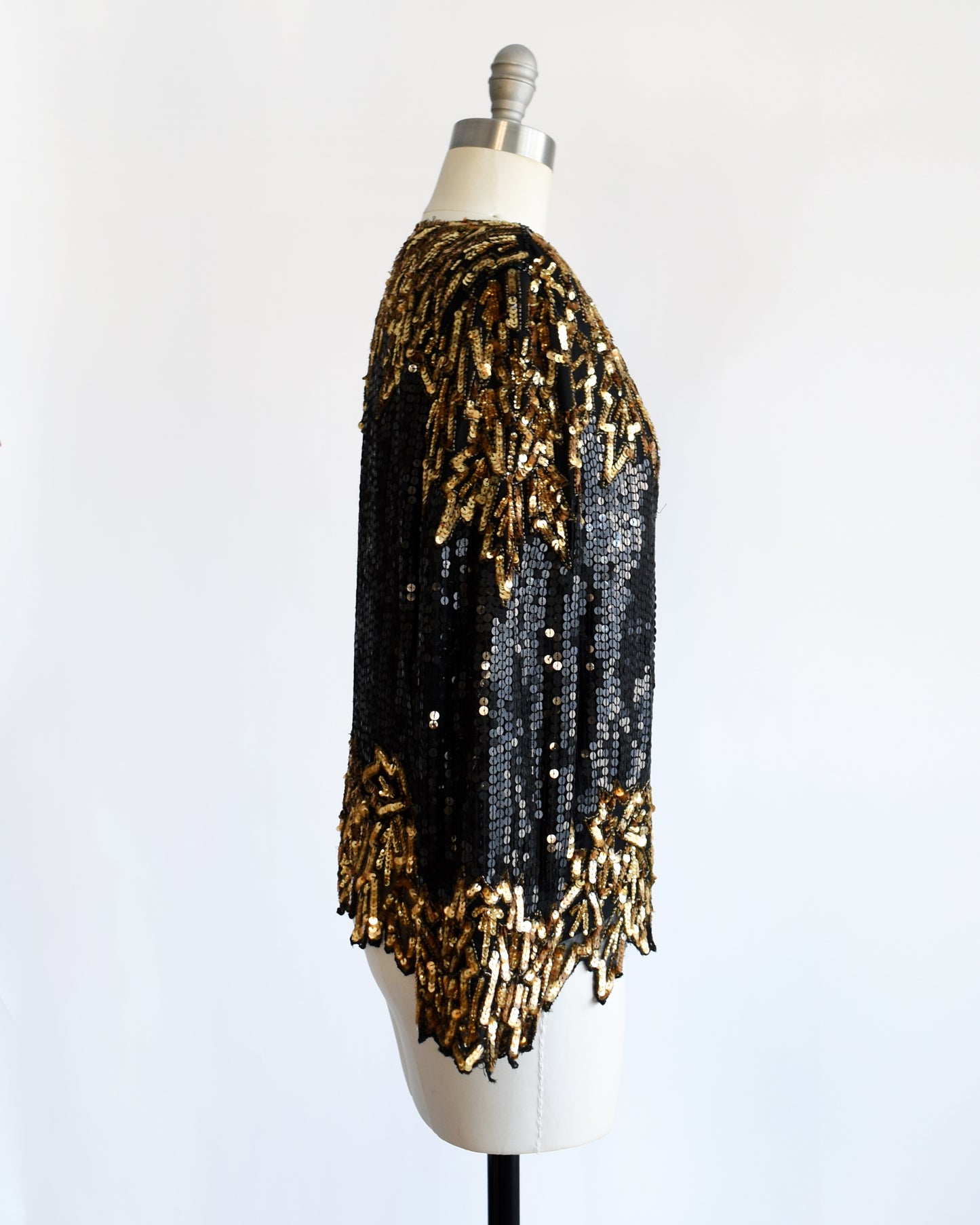 side view of a vintage 1980s black and gold sequin top on a mannequin against a white background
