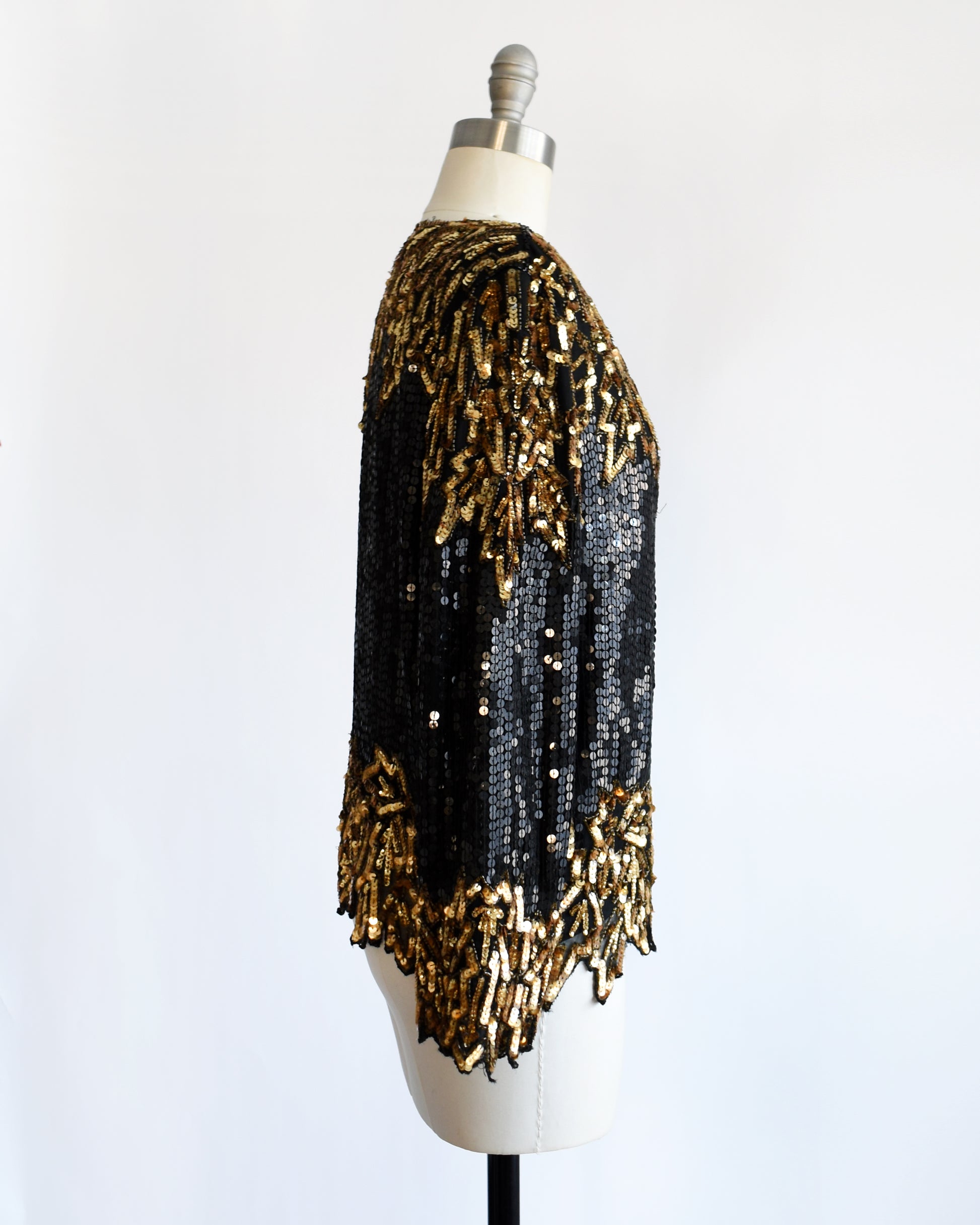 side view of a vintage 1980s black and gold sequin top on a mannequin against a white background