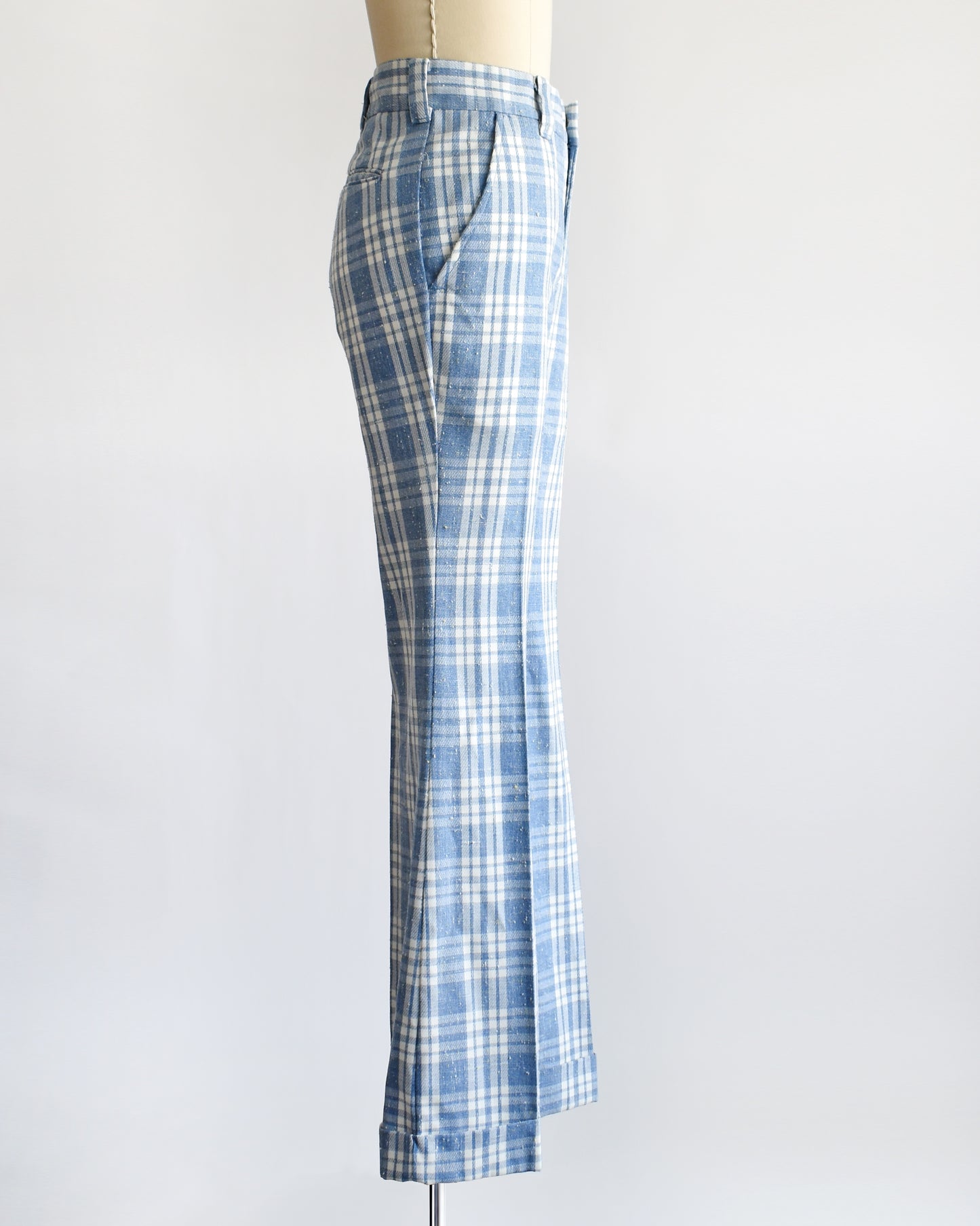 side view of vintage 1970s blue and white plaid wide-leg pants displayed on a cream dress form mannequin against a plain white background.