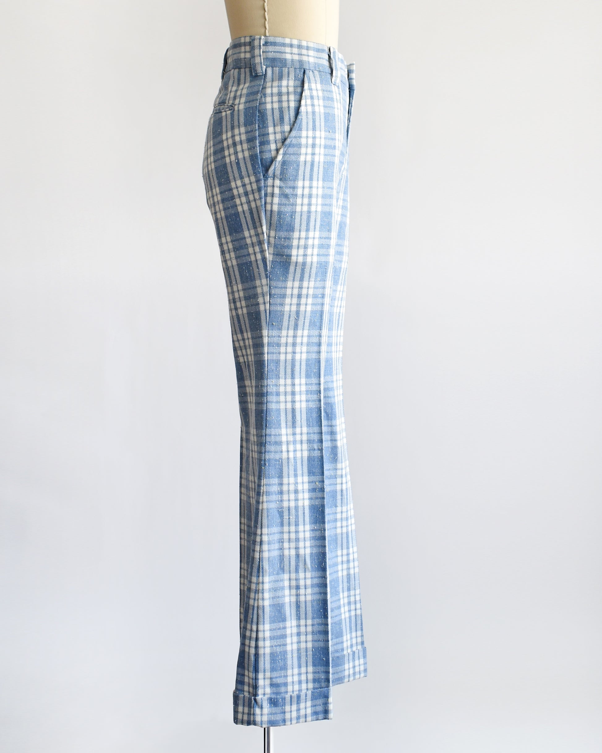 side view of vintage 1970s blue and white plaid wide-leg pants displayed on a cream dress form mannequin against a plain white background.