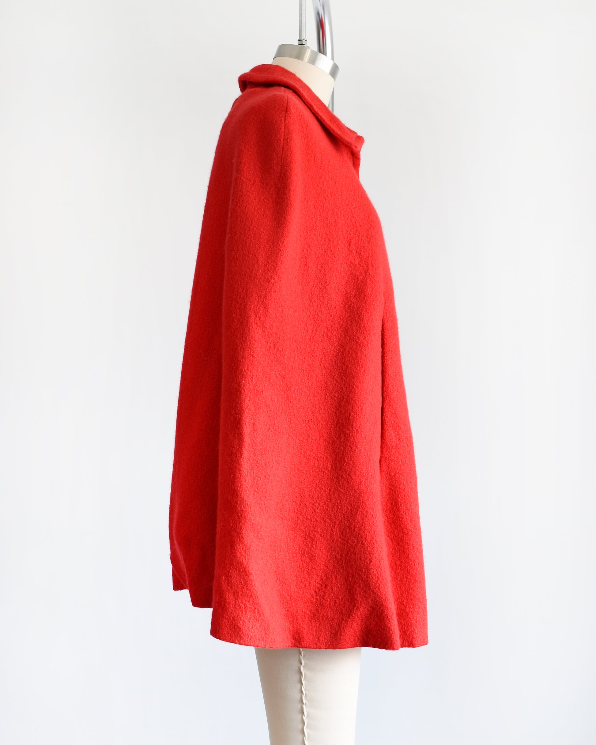 side view of a vintage 1960s red cape with zip up front, front arm slits, and collared neckline.