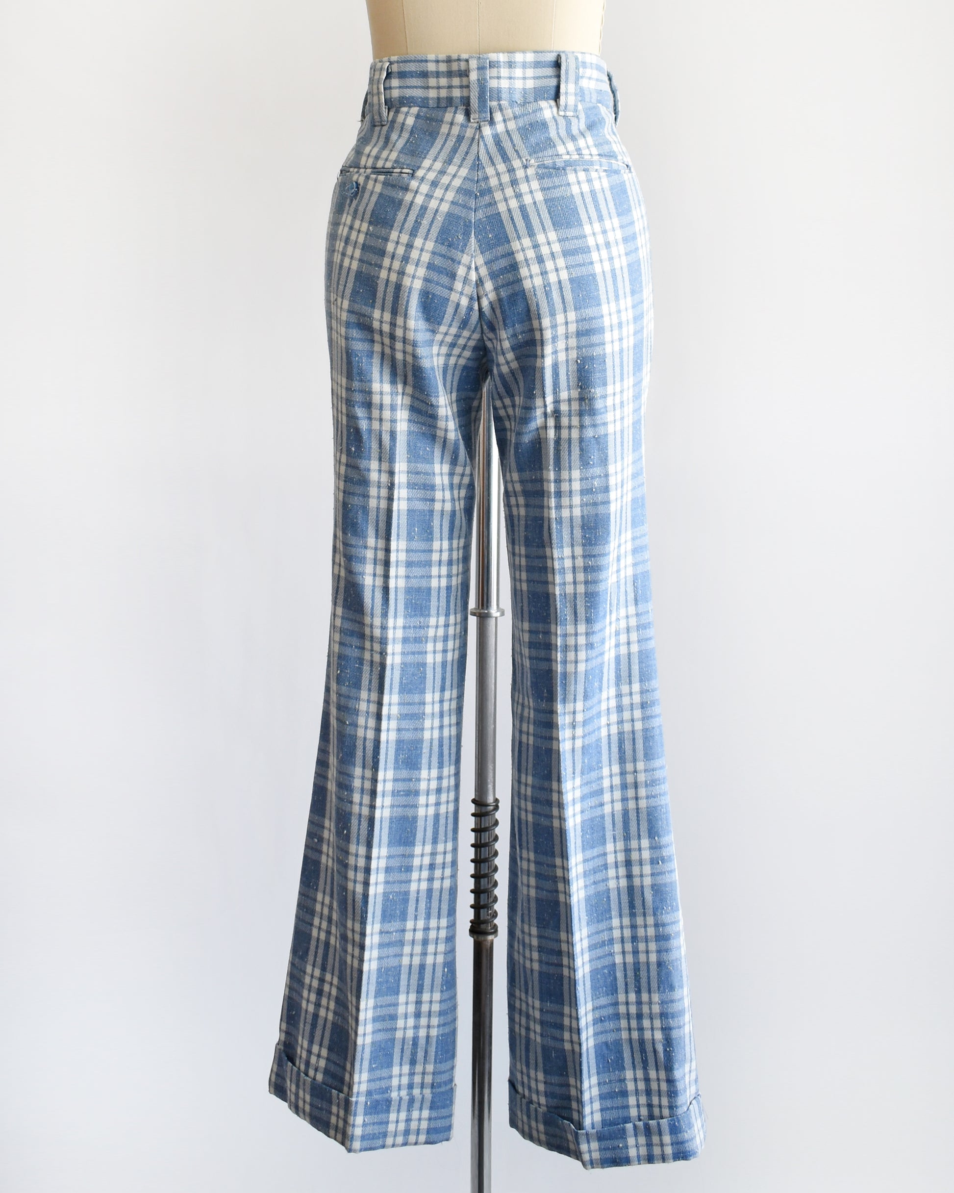 back view of vintage 1970s blue and white plaid wide-leg pants displayed on a cream dress form mannequin against a plain white background.