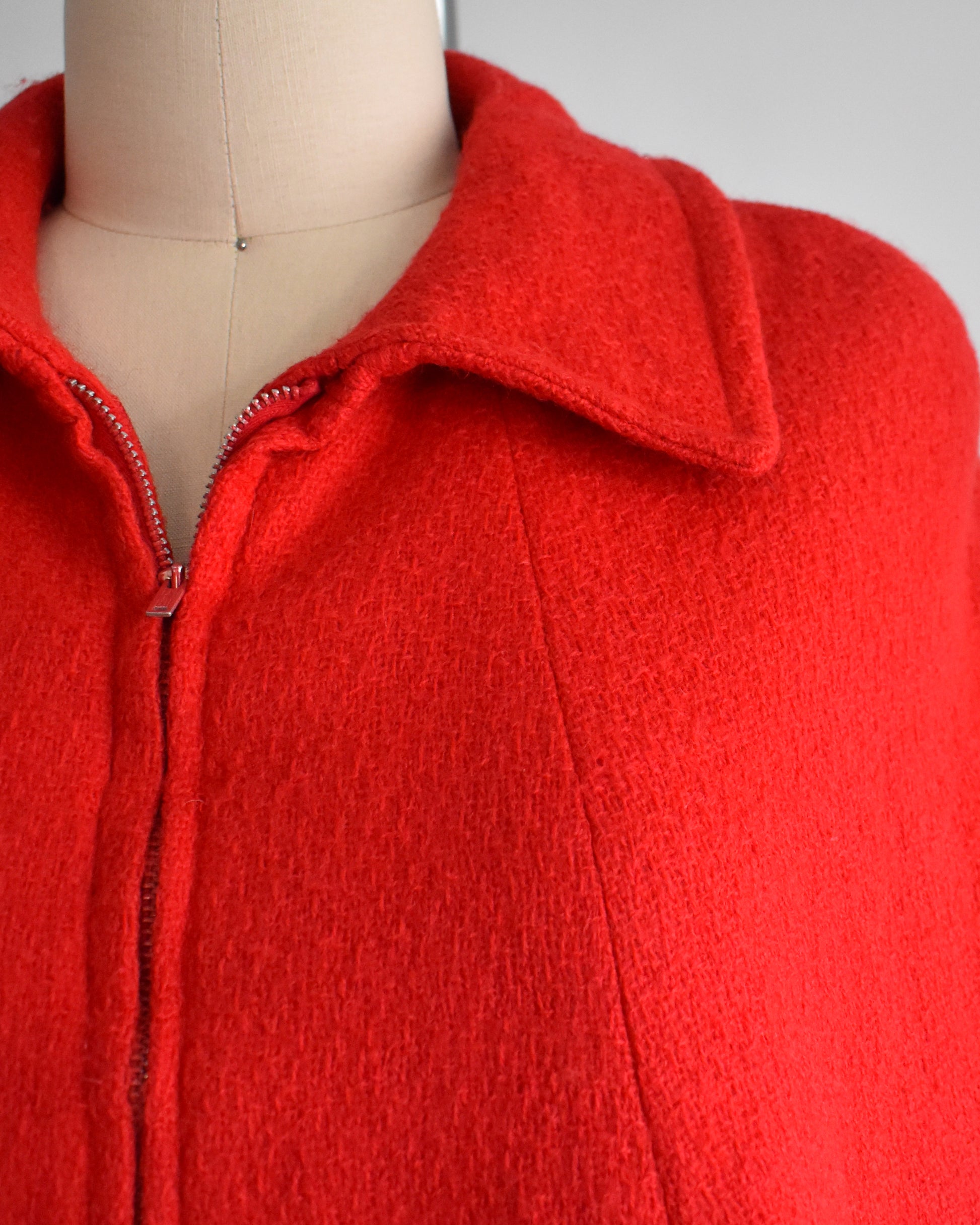 close up of the collared neckline, zipper, and red wool on a vintage 1960s cape