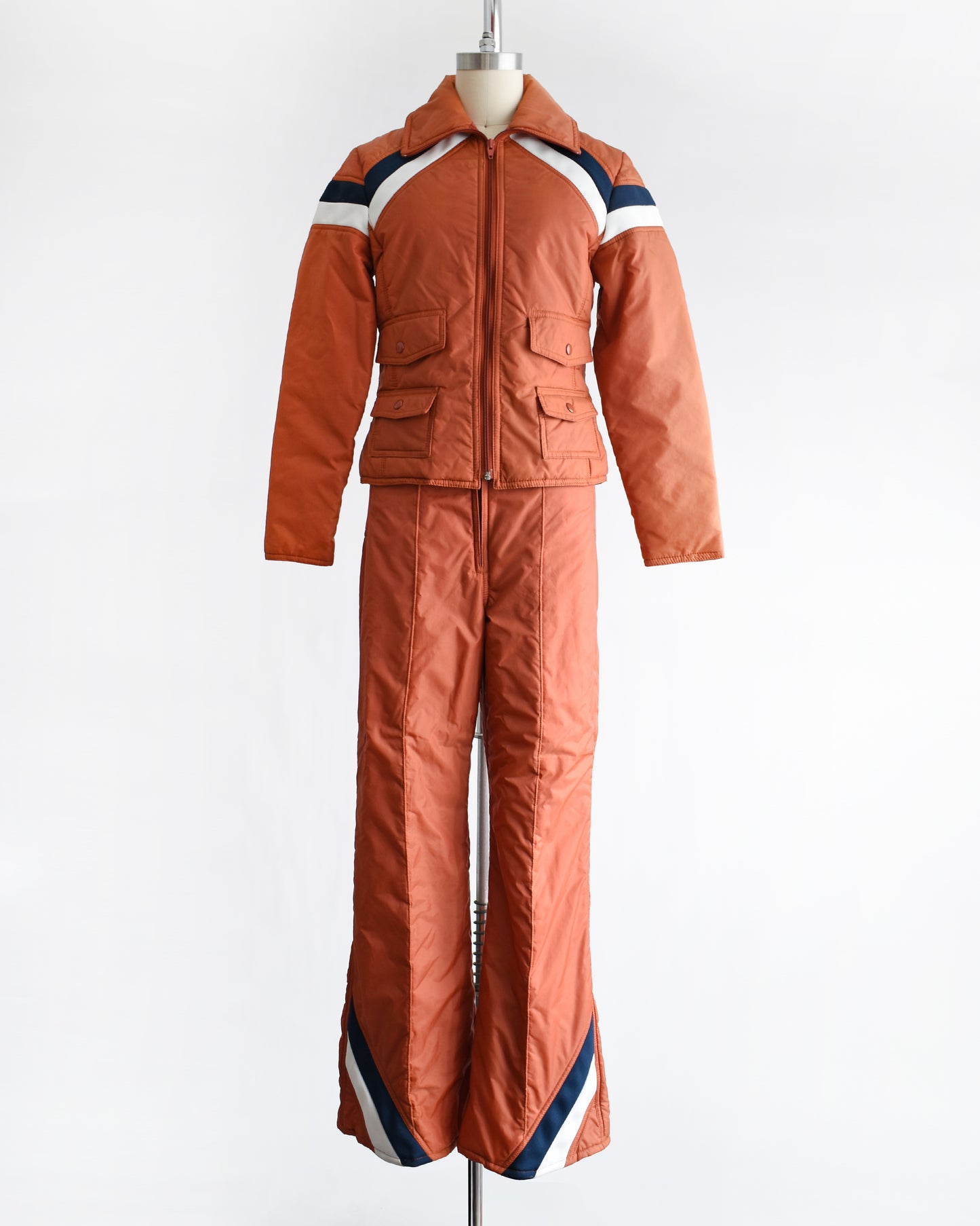a vintage 1970s orange winter ski suit on a mannequin against a white background