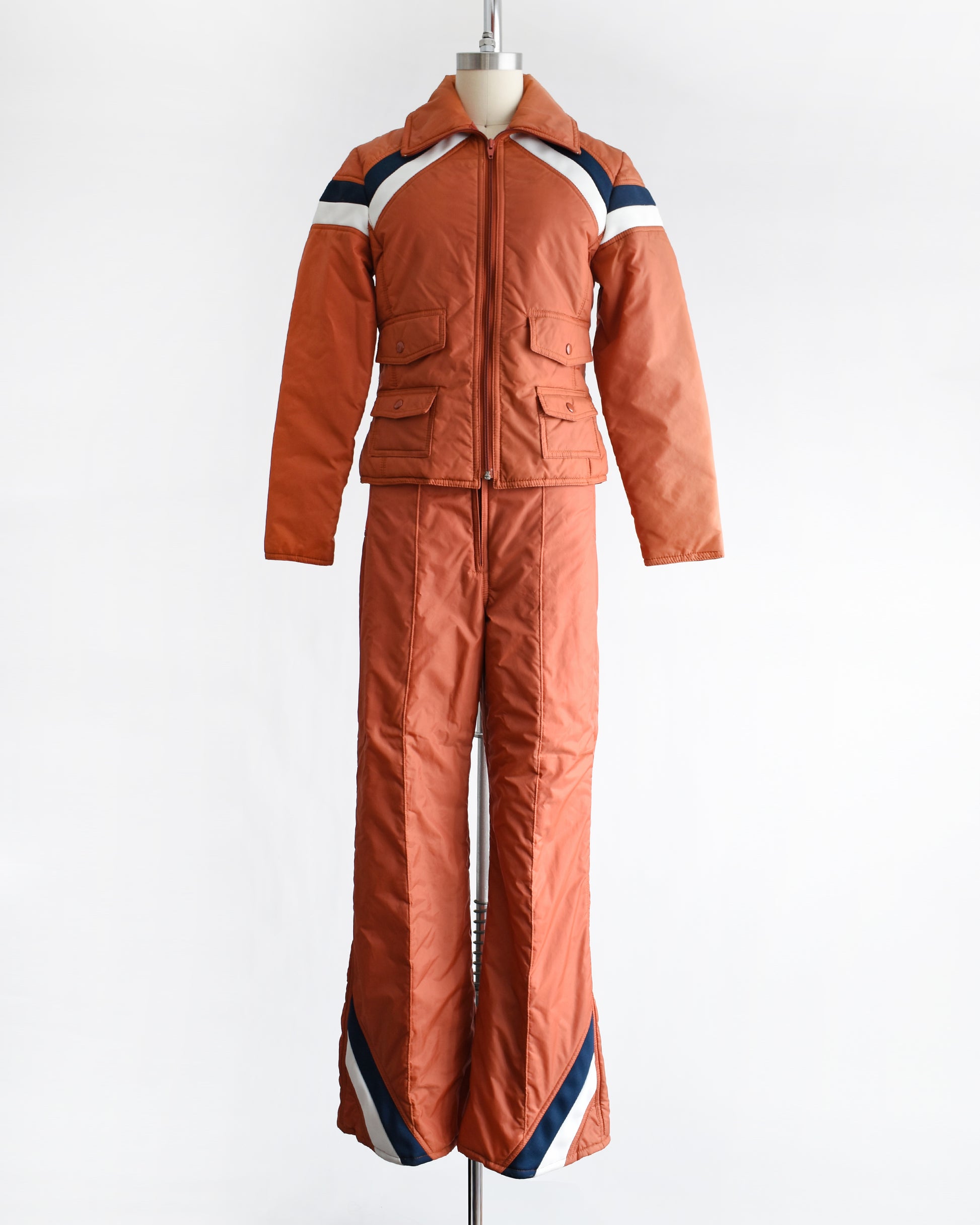 a vintage 1970s orange winter ski suit on a mannequin against a white background
