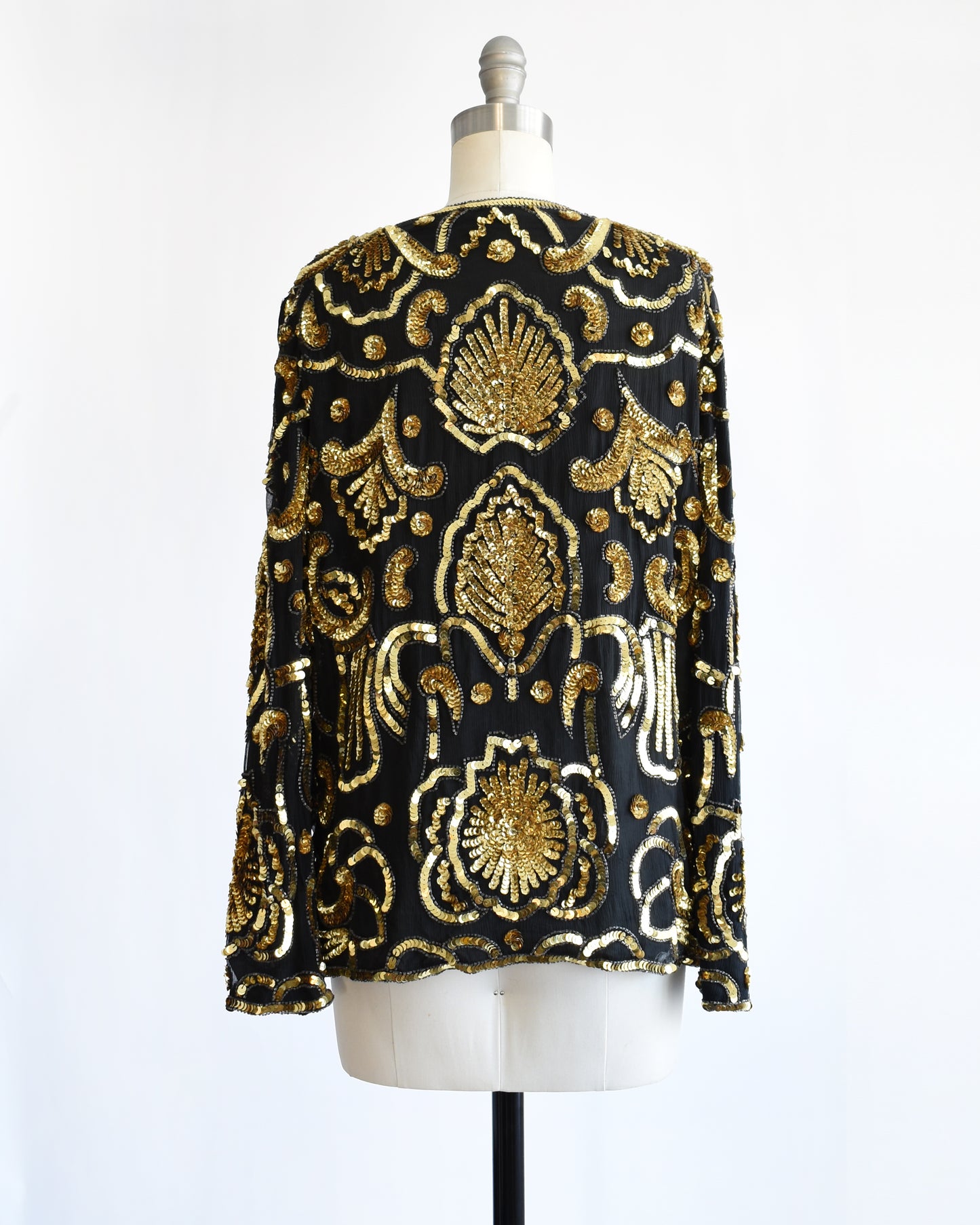 back view of a black and gold vintage sequin jacket on a mannequin against a white background