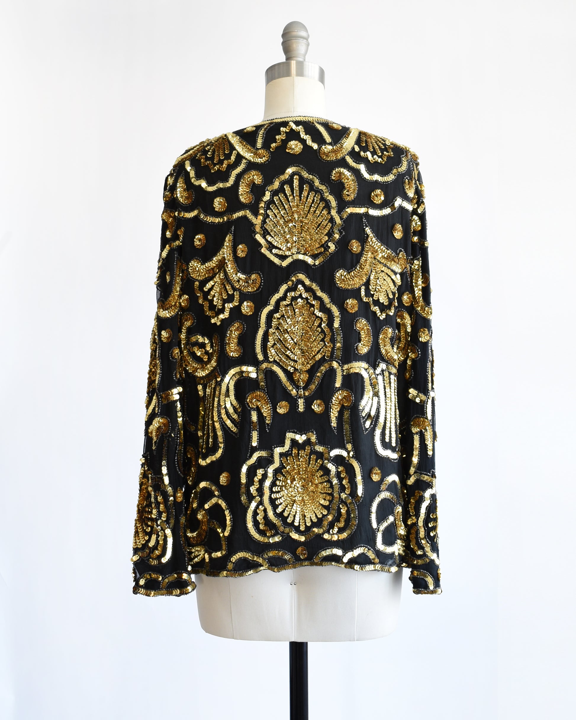 back view of a black and gold vintage sequin jacket on a mannequin against a white background