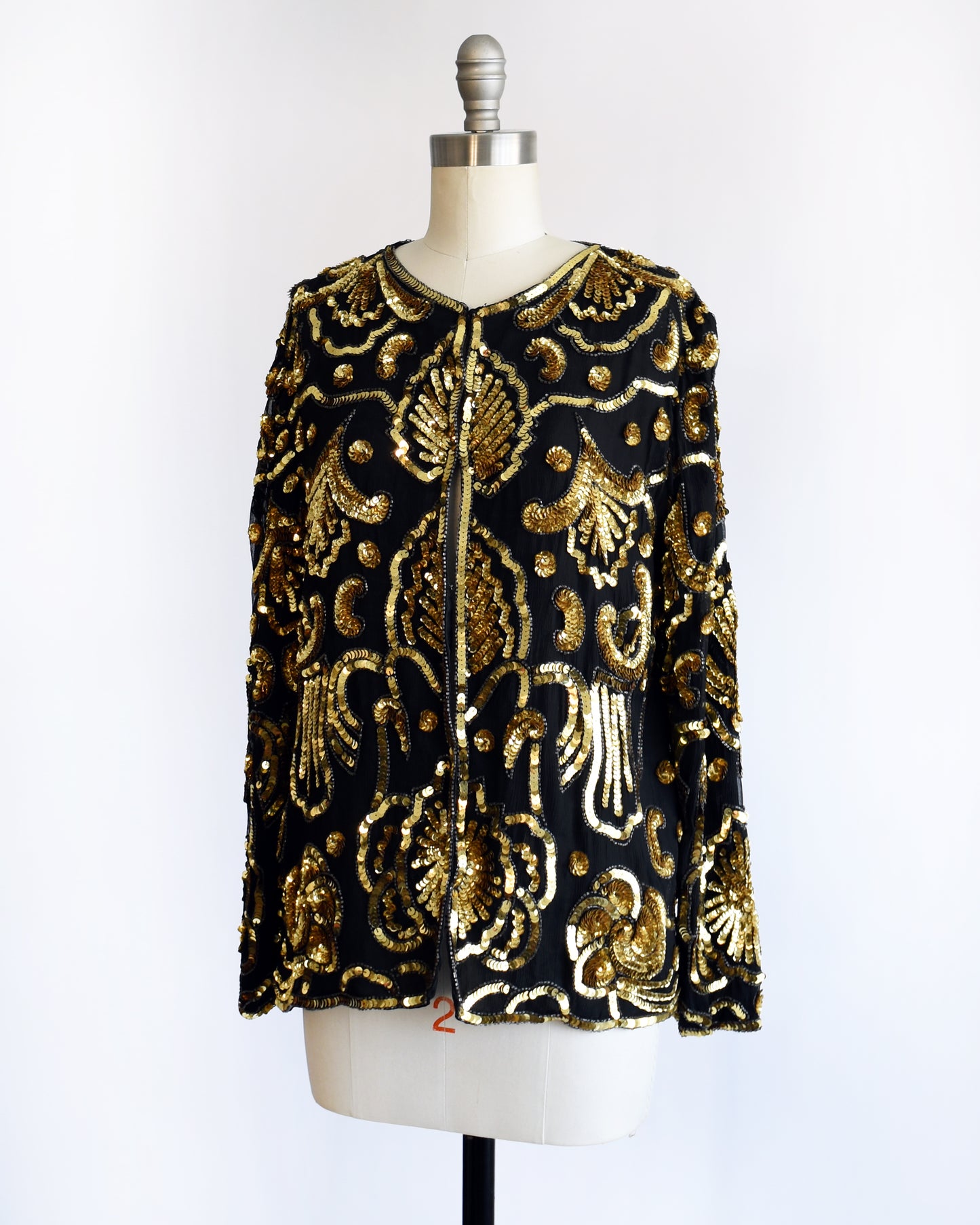 side front view of a black and gold vintage sequin jacket on a mannequin against a white background