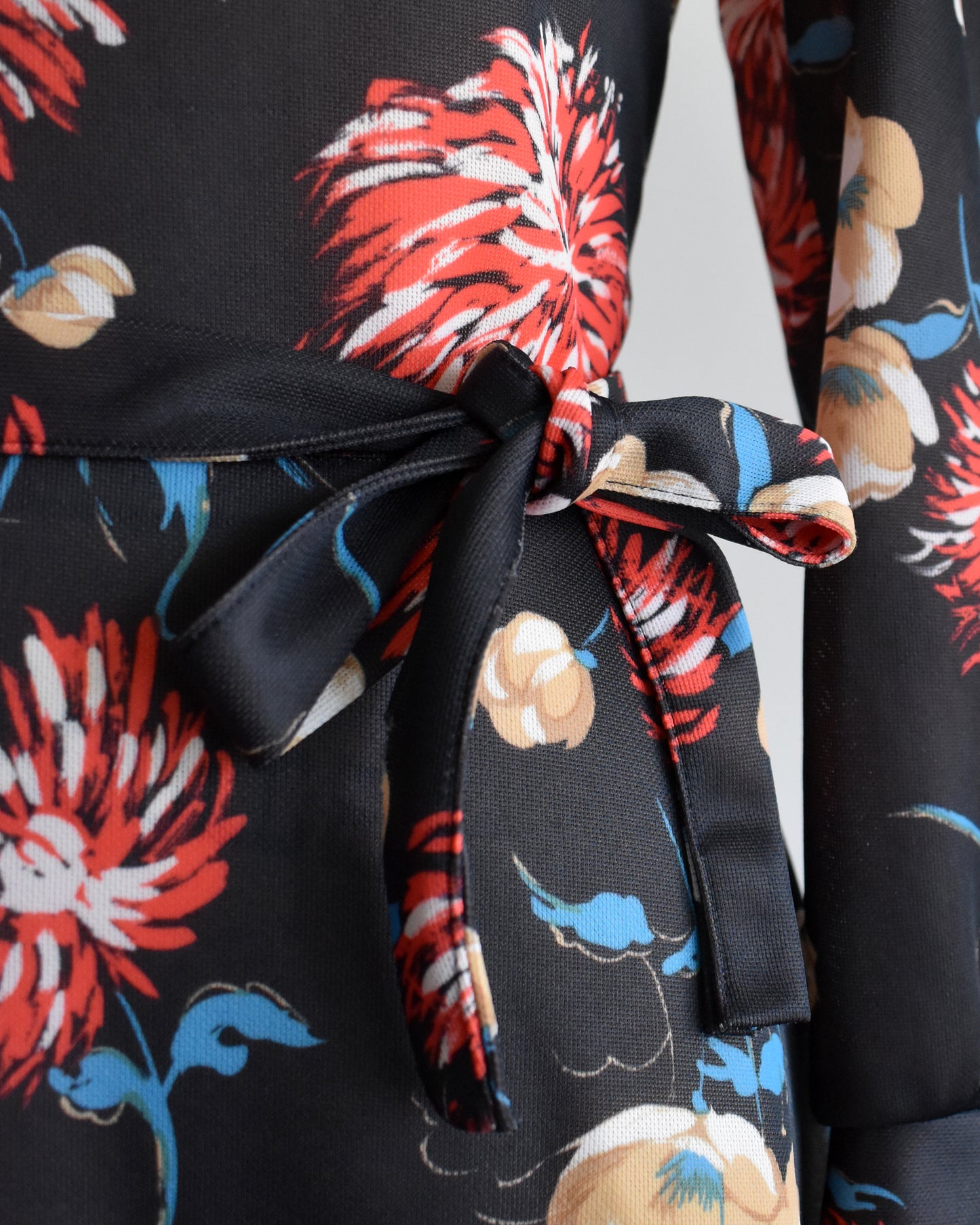 close up of the waist of the dress which shows the large floral print and matching tie belt