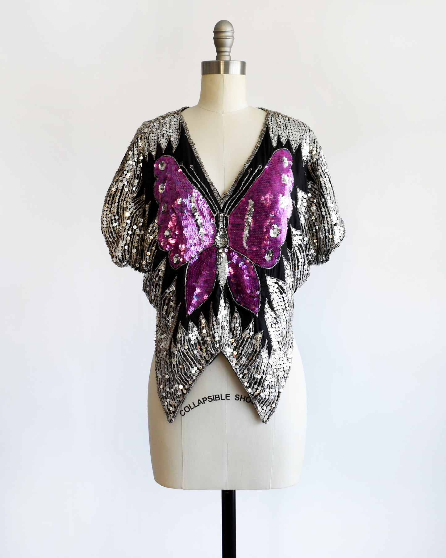 a vintage 1970s / 1980s sequined top with butterfly design on a mannequin against a white background