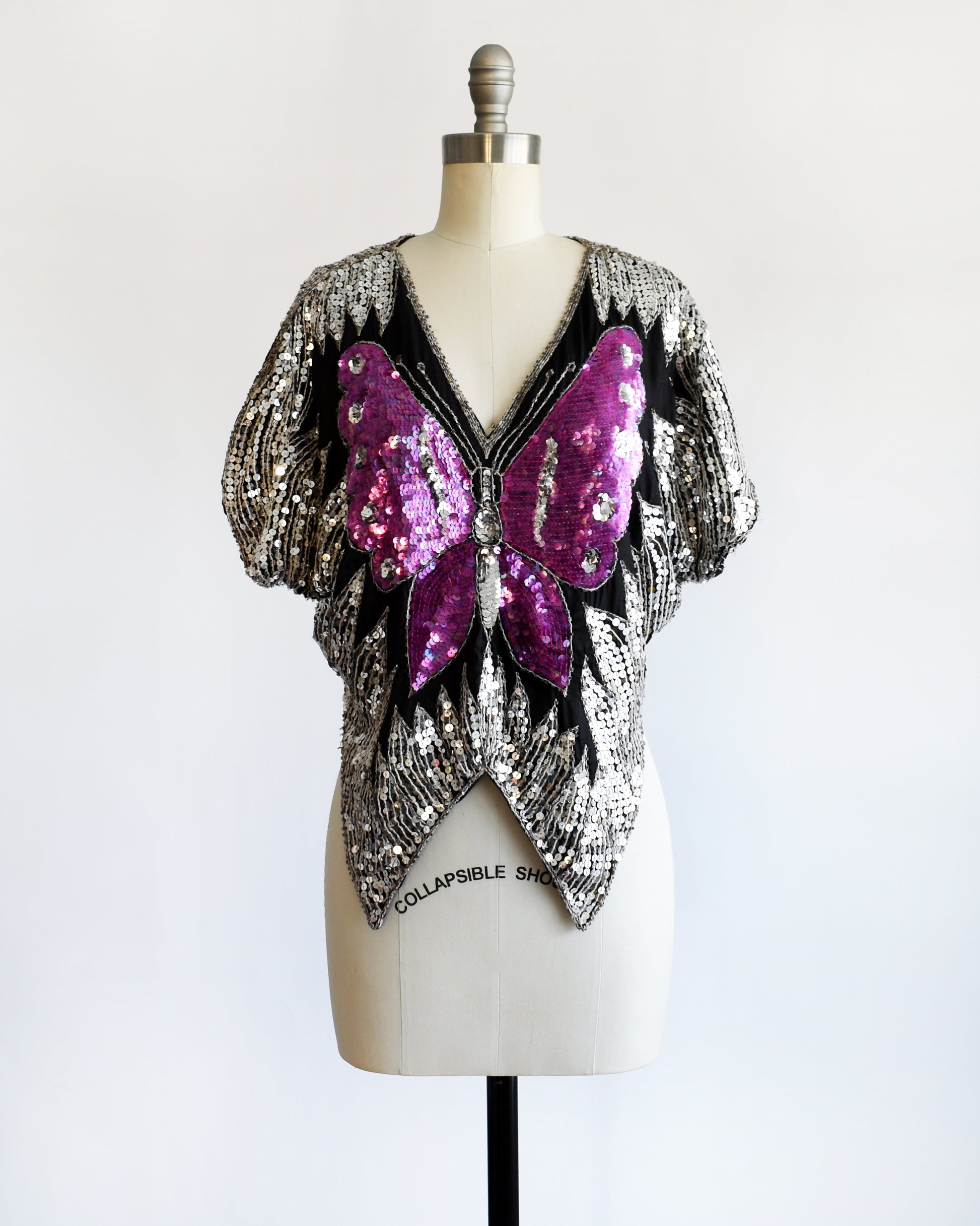 a vintage 1970s / 1980s sequined top with butterfly design on a mannequin against a white background