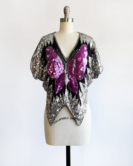 a vintage 1970s / 1980s sequined top with butterfly design on a mannequin against a white background
