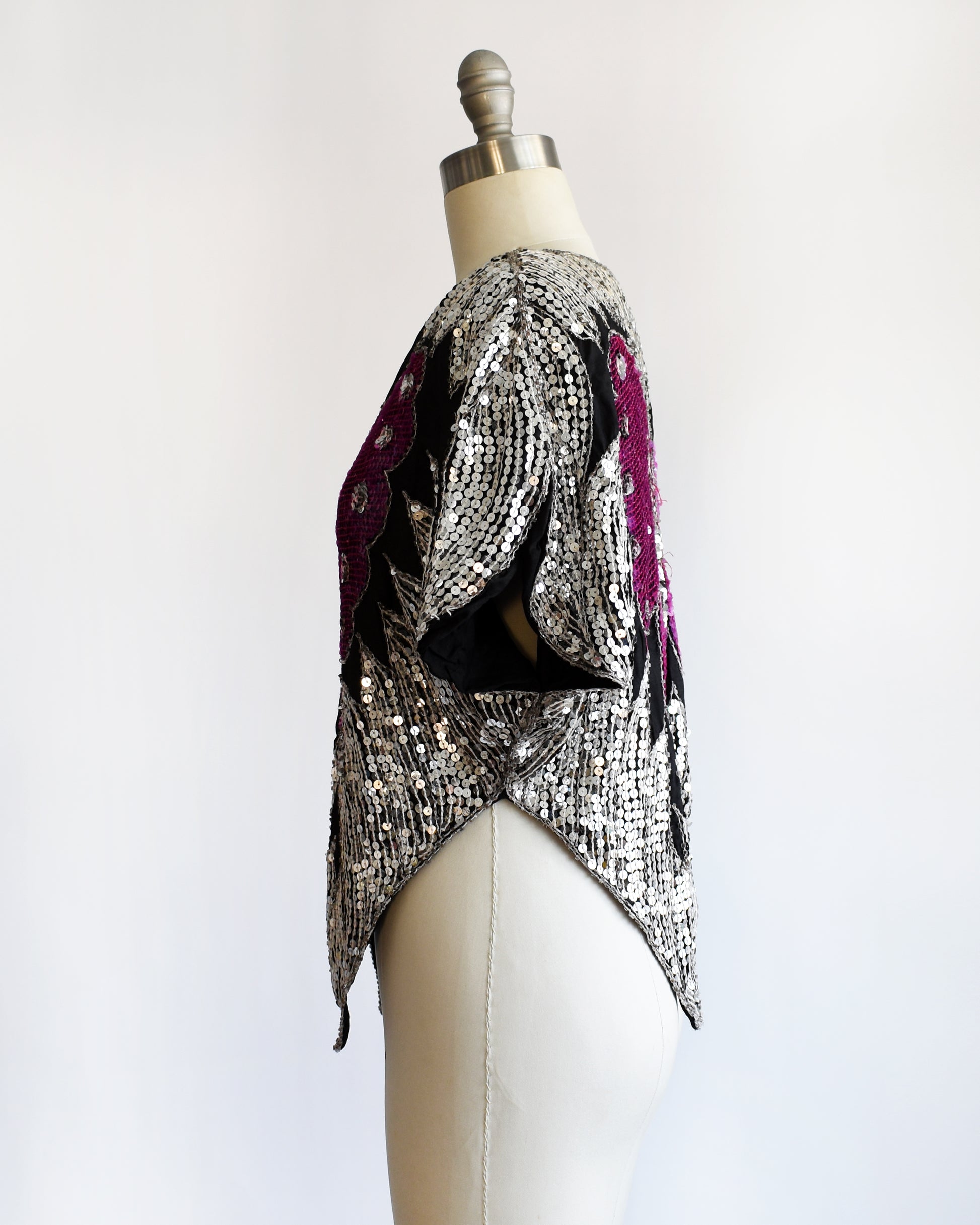 side view of a vintage 1970s / 1980s sequined top with butterfly design on a mannequin against a white background