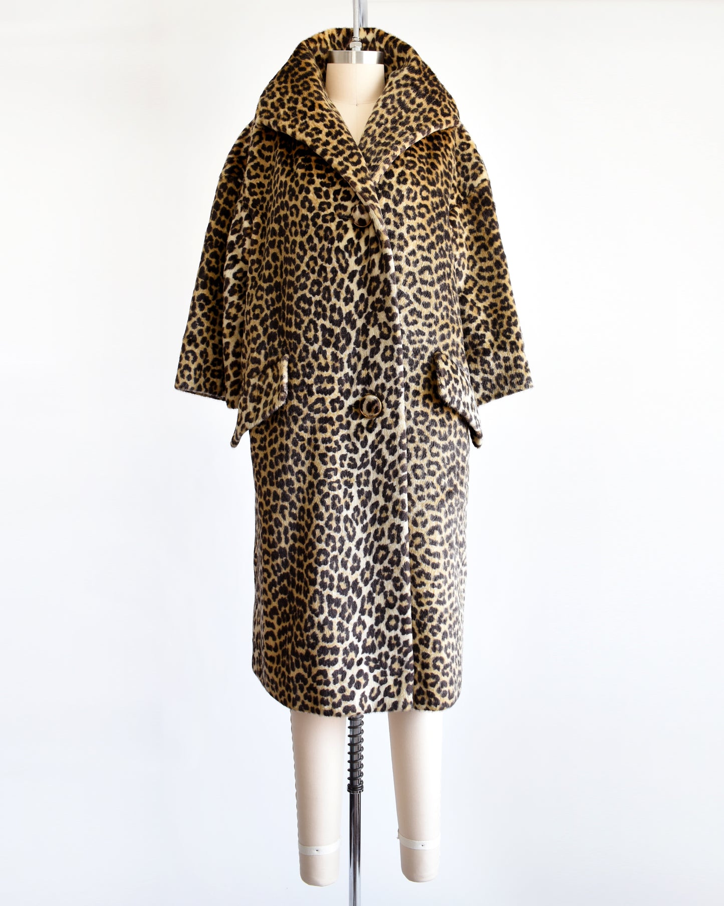 A vintage 1960s faux fur leopard print coat on a dress form. The collar is pulled up in this photo.