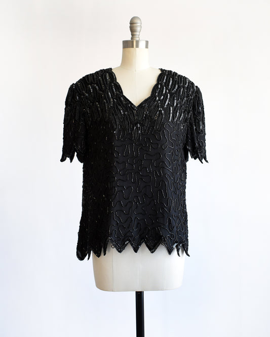 a vintage 1980s black sequin and beaded top on a mannequin against a white background