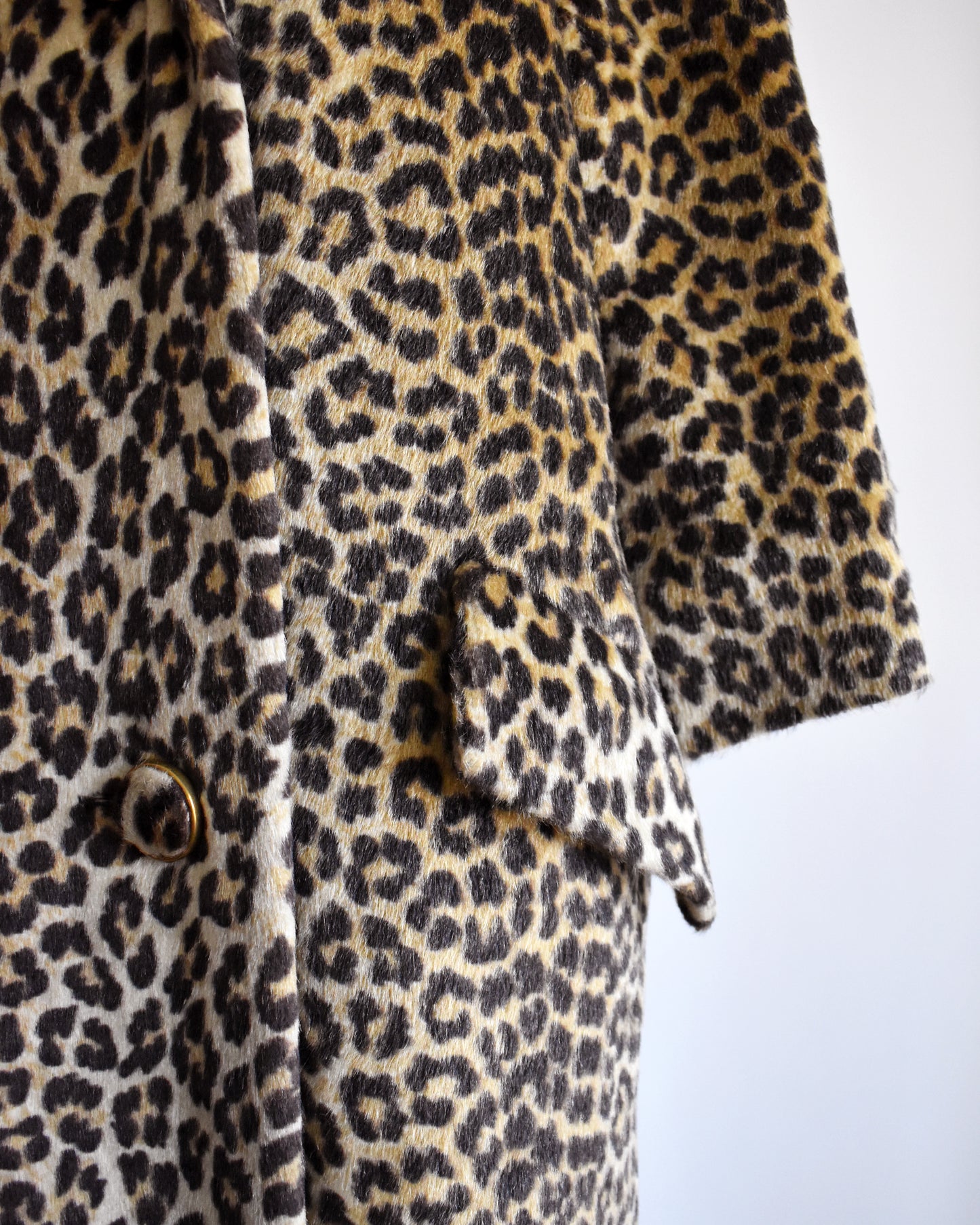 Close up of the pocket flap of a vintage 1960s faux fur leopard print coat on a dress form