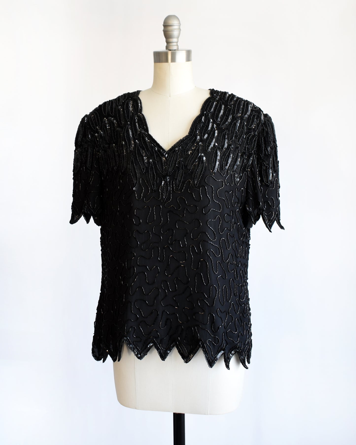 side front view of a vintage 1980s black sequin and beaded top on a mannequin against a white background