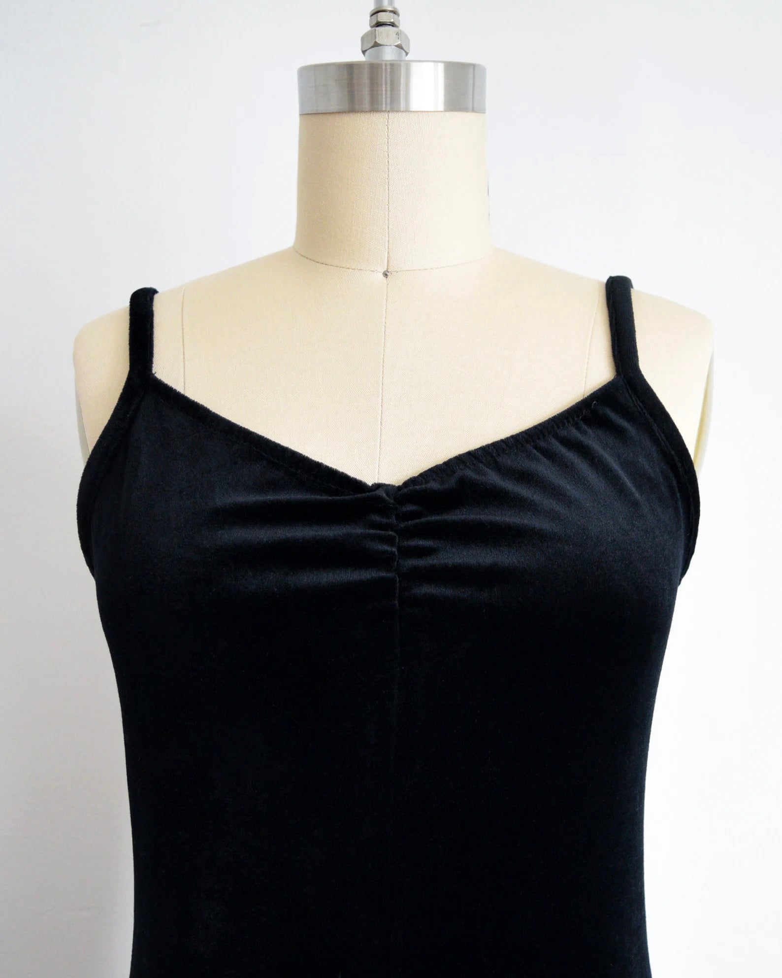 A black velvet jumpsuit displayed on a mannequin against a white wall