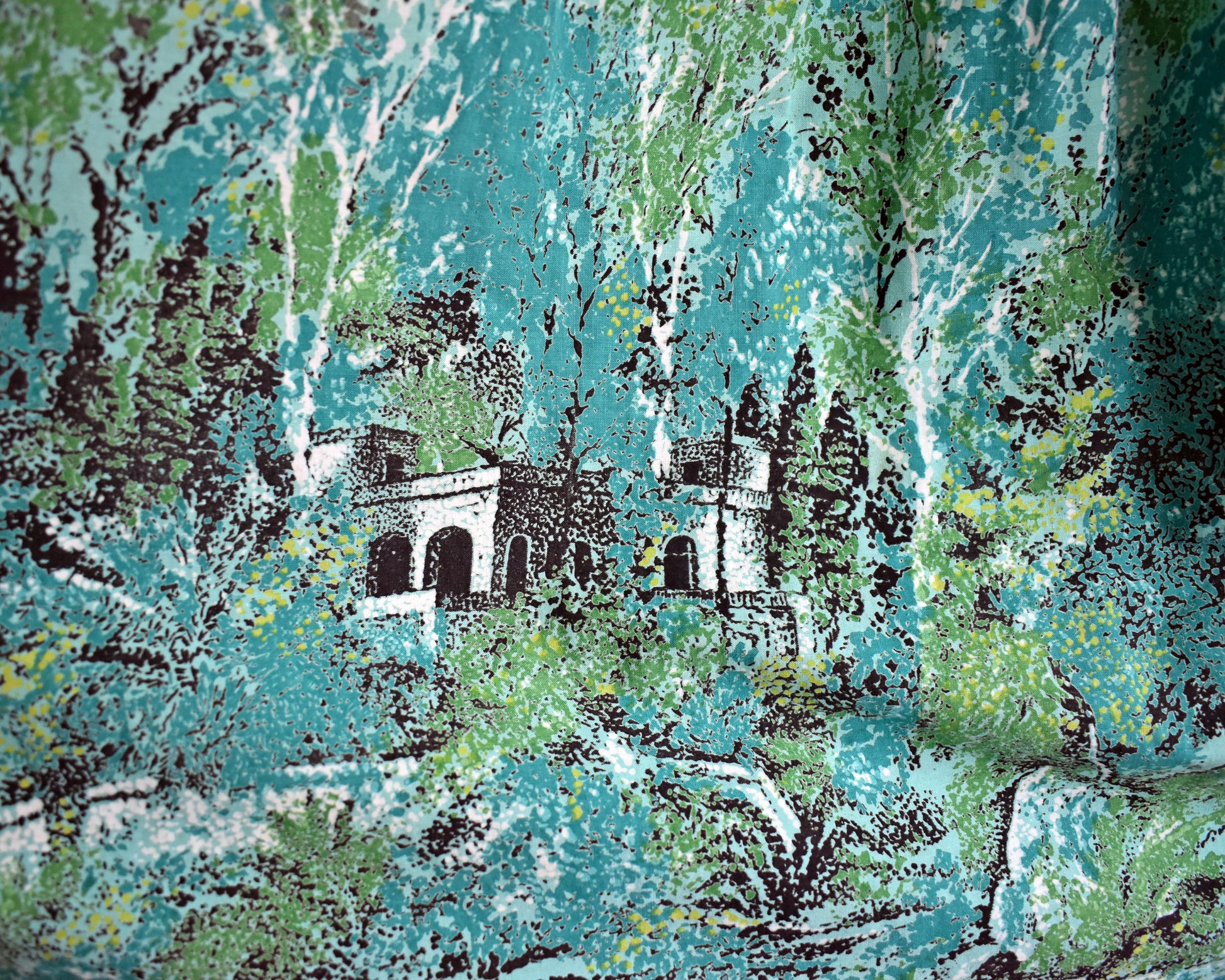 close up of the scenic novelty print which includes lots of trees an a chateau looking abode