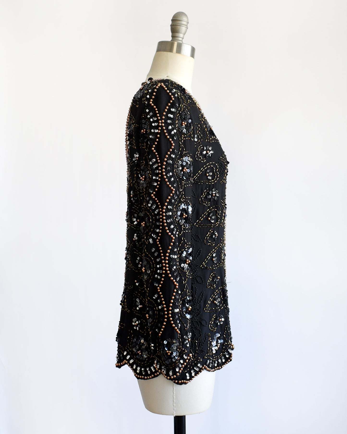side view of a vintage 1980s black sequin and beaded top on a mannequin against a white background