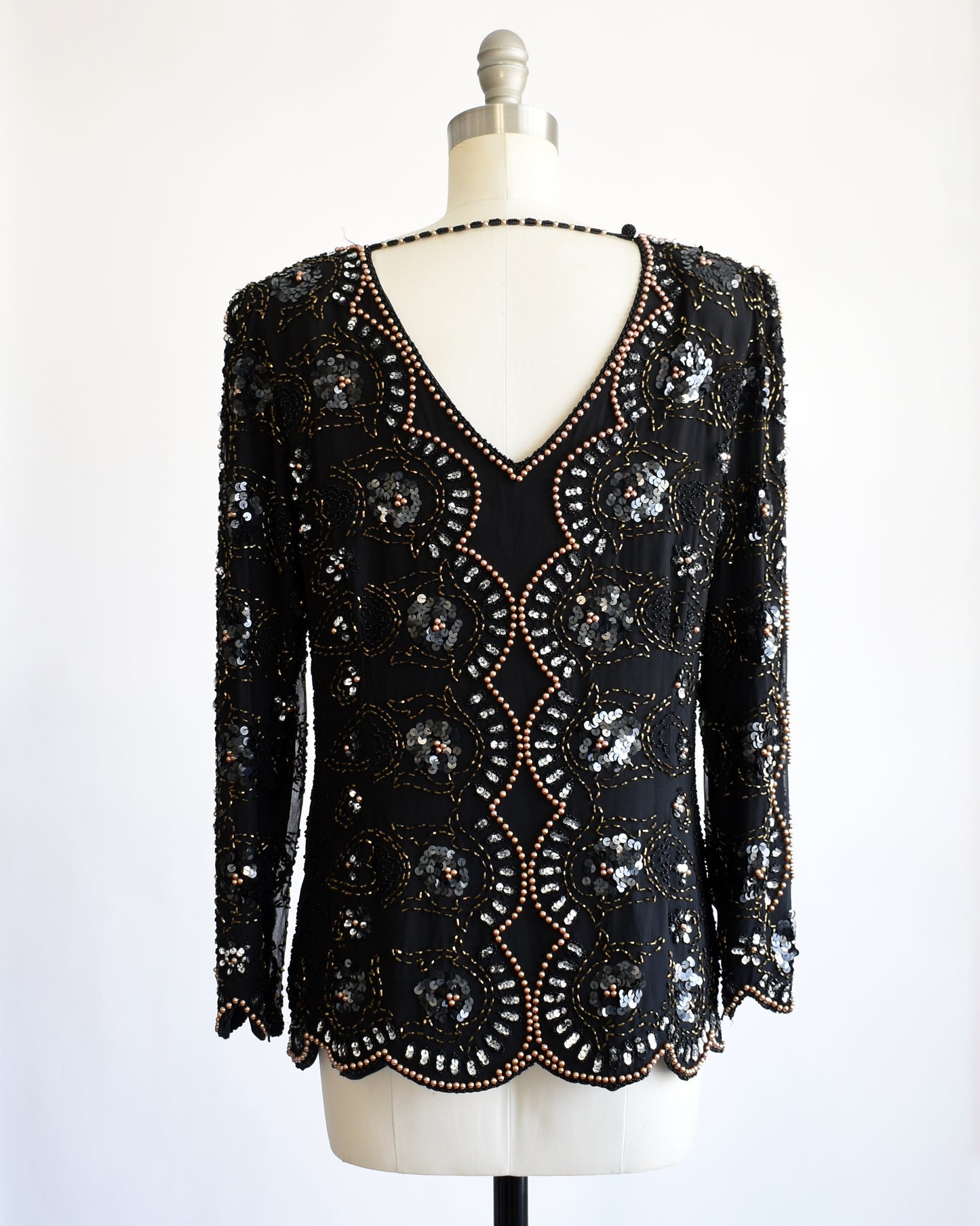 back view of a vintage 1980s black sequin and beaded top on a mannequin against a white background