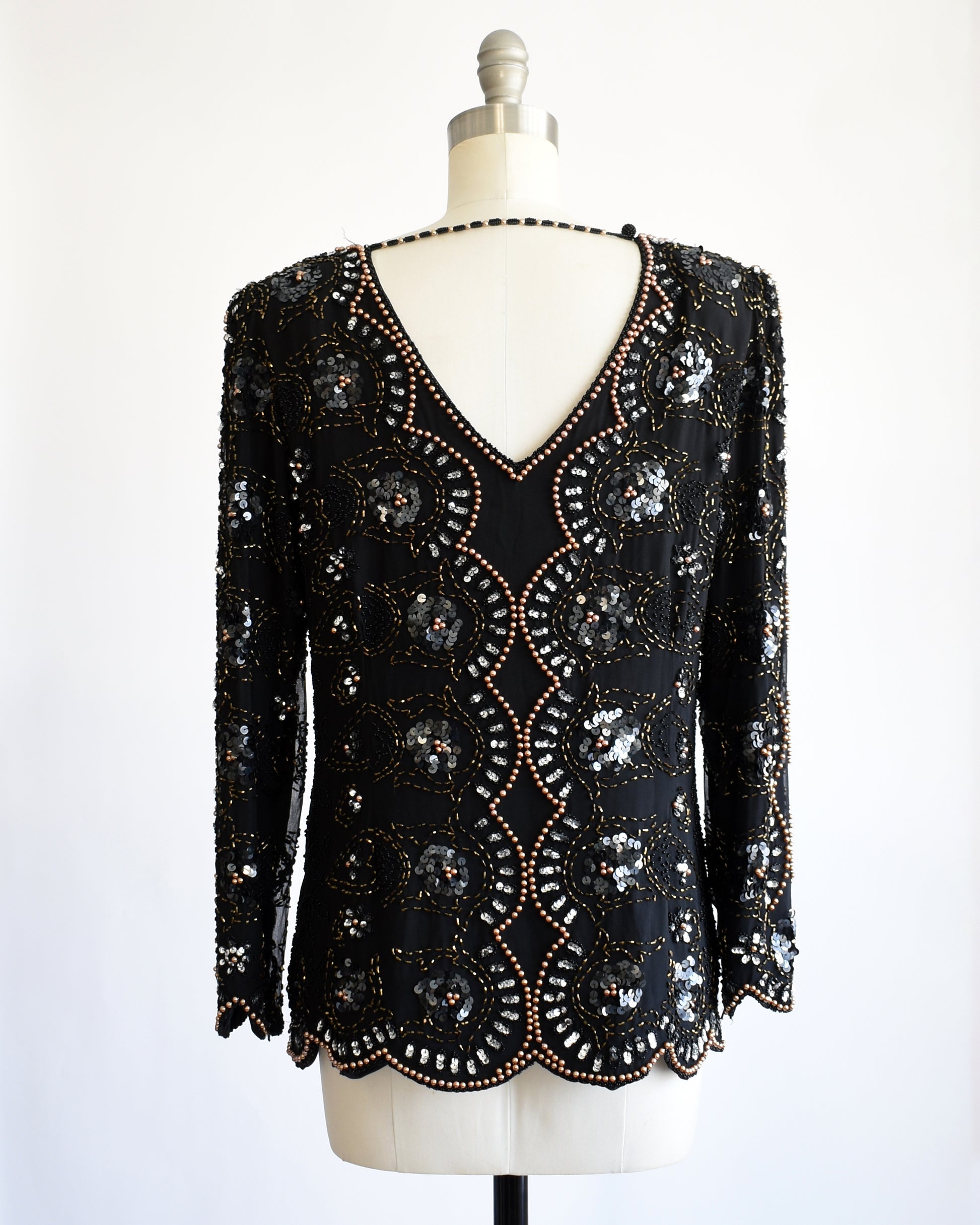 back view of a vintage 1980s black sequin and beaded top on a mannequin against a white background