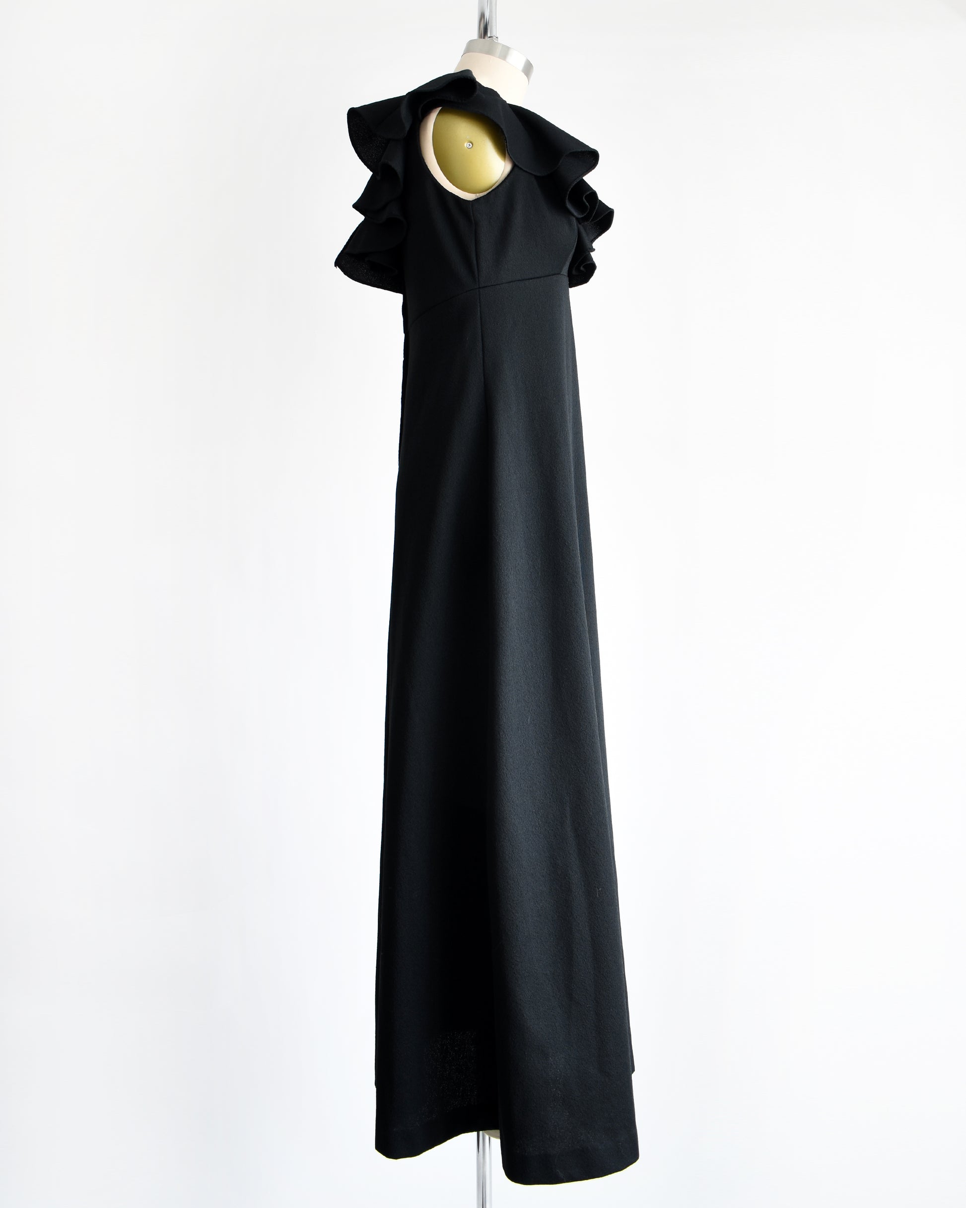 side view of a vintage black 1970s maxi dress with a ruffled neckline.