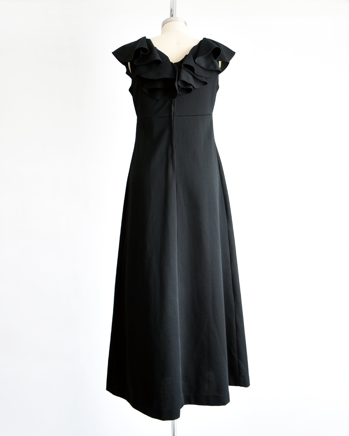 back view of a vintage black 1970s maxi dress with a ruffled neckline.