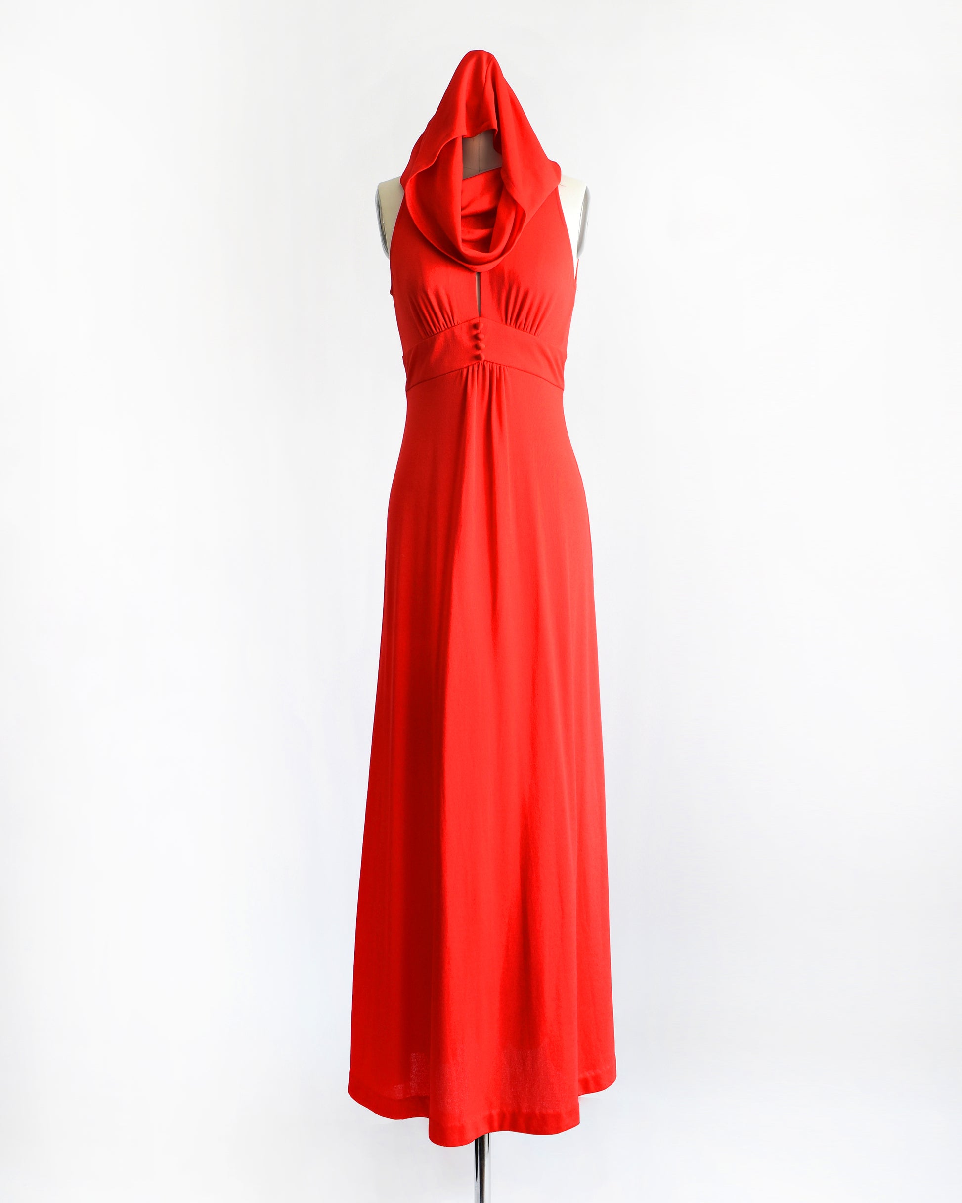 A bright vintage 1970s red halter-neck hooded maxi dress displayed on a mannequin against a plain white background.
