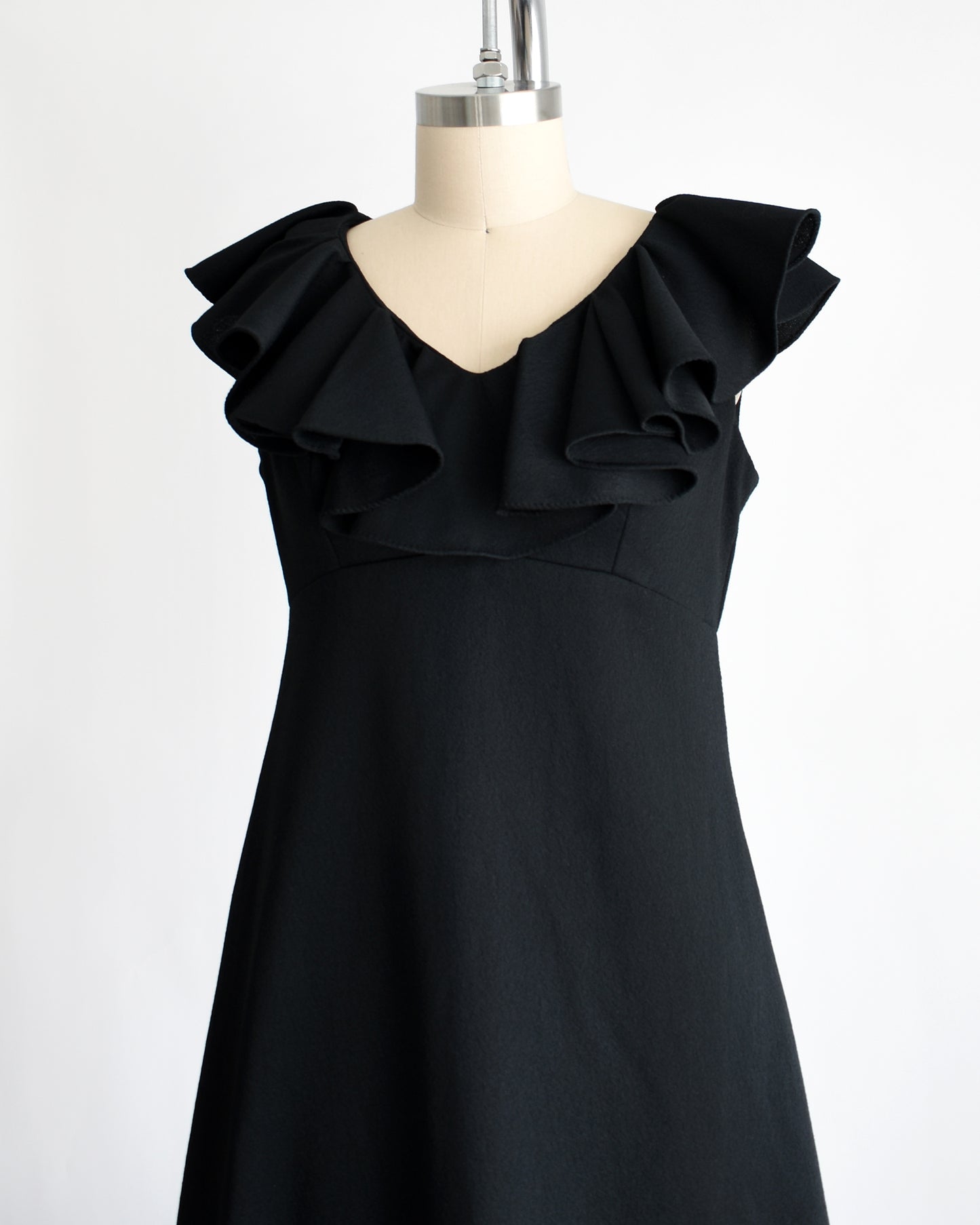 side front view of a vintage black 1970s maxi dress with a ruffled neckline.