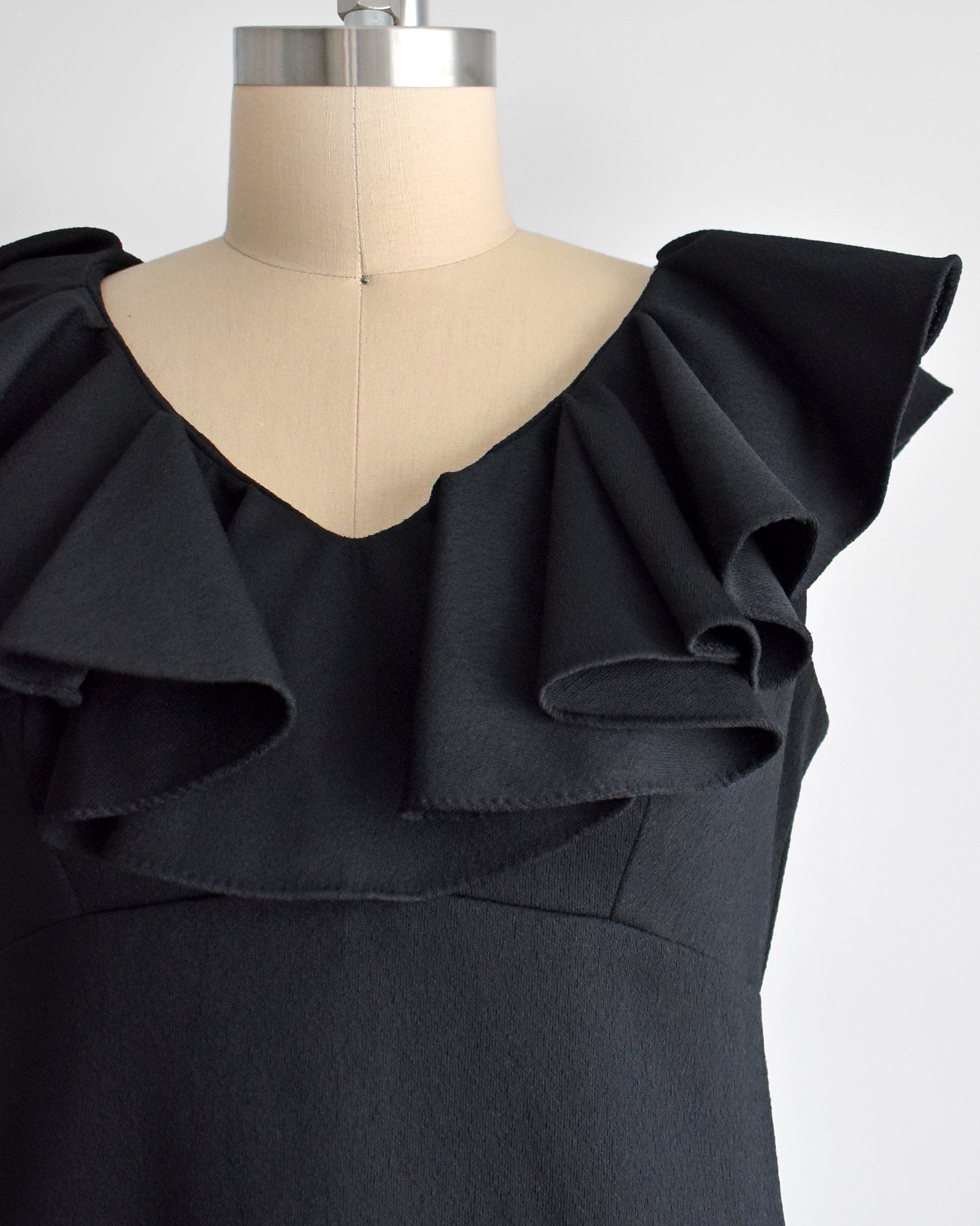 close up of the ruffled neckline on a vintage 1960s black maxi dress