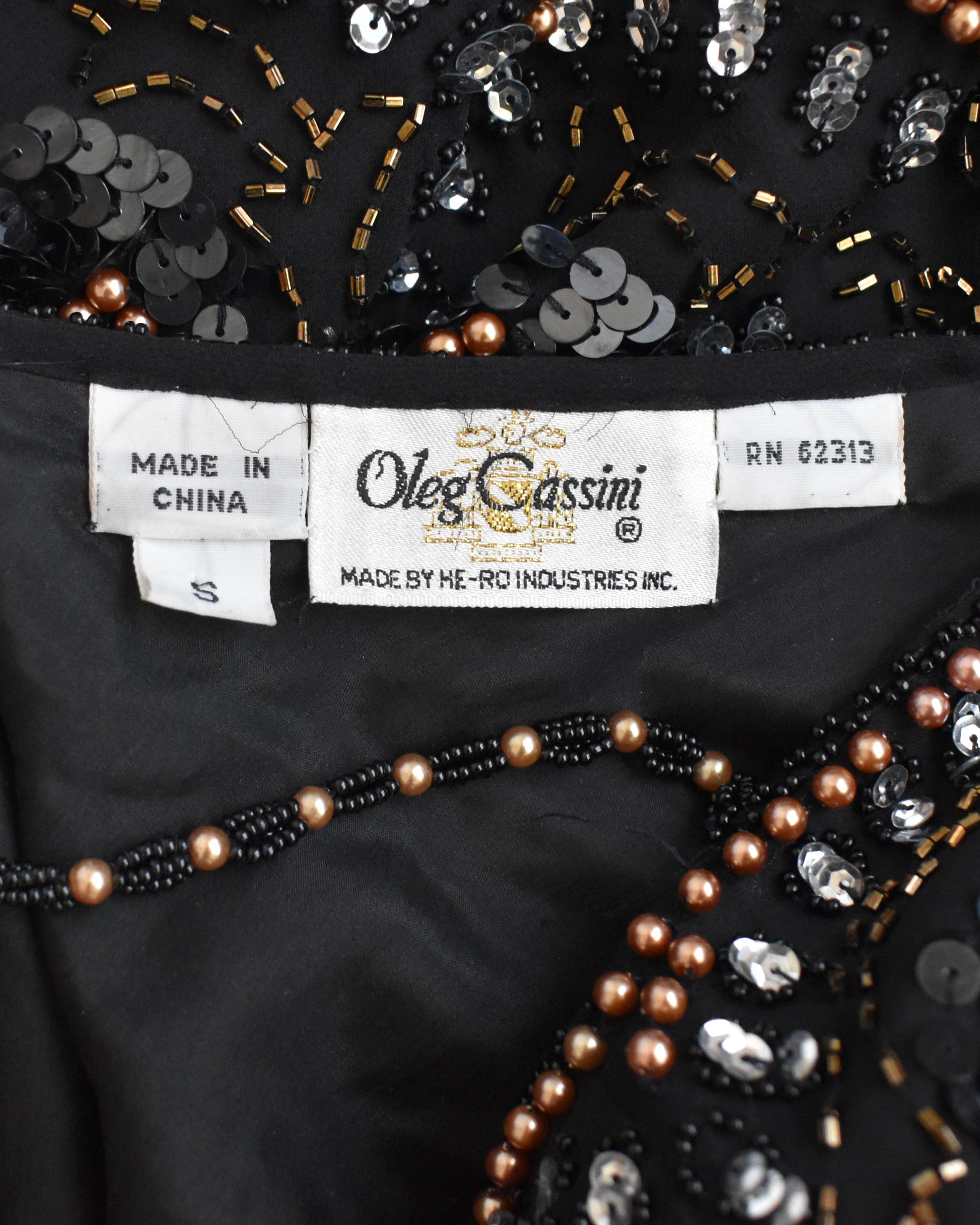 Close-up of a label on an embellished garment with 'Oleg Cassini' branding.