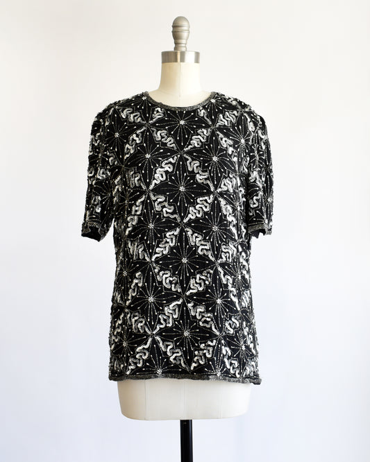 a vintage 1980s black and silver sequin beaded patterned top on a mannequin against a white background