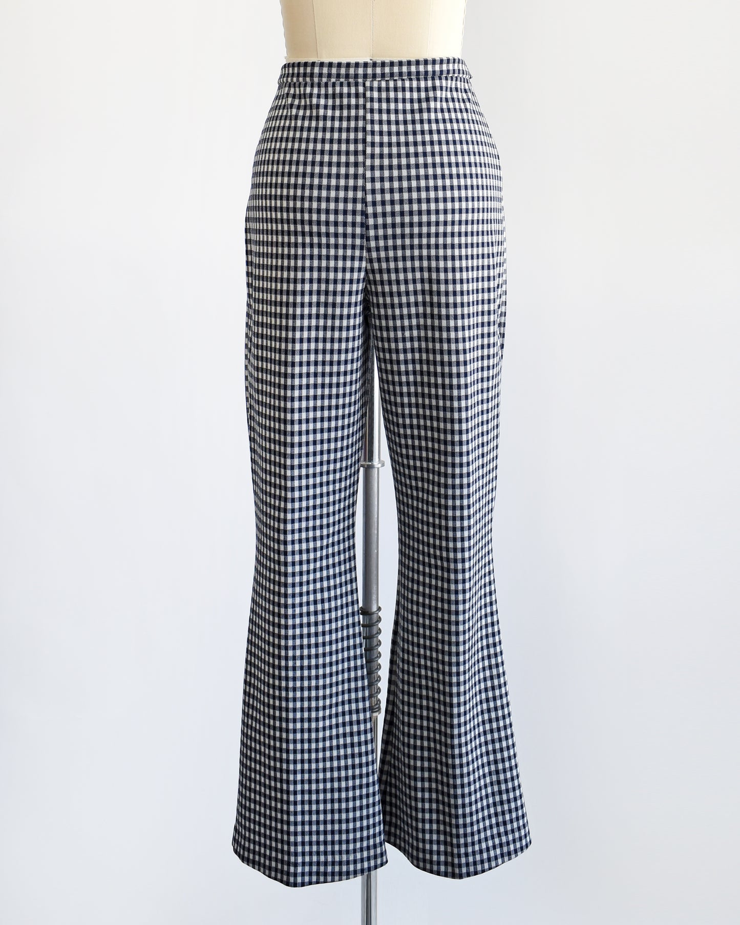 back view of a pair of vintage 1970s blue and white gingham bell bottom pants on a dress form