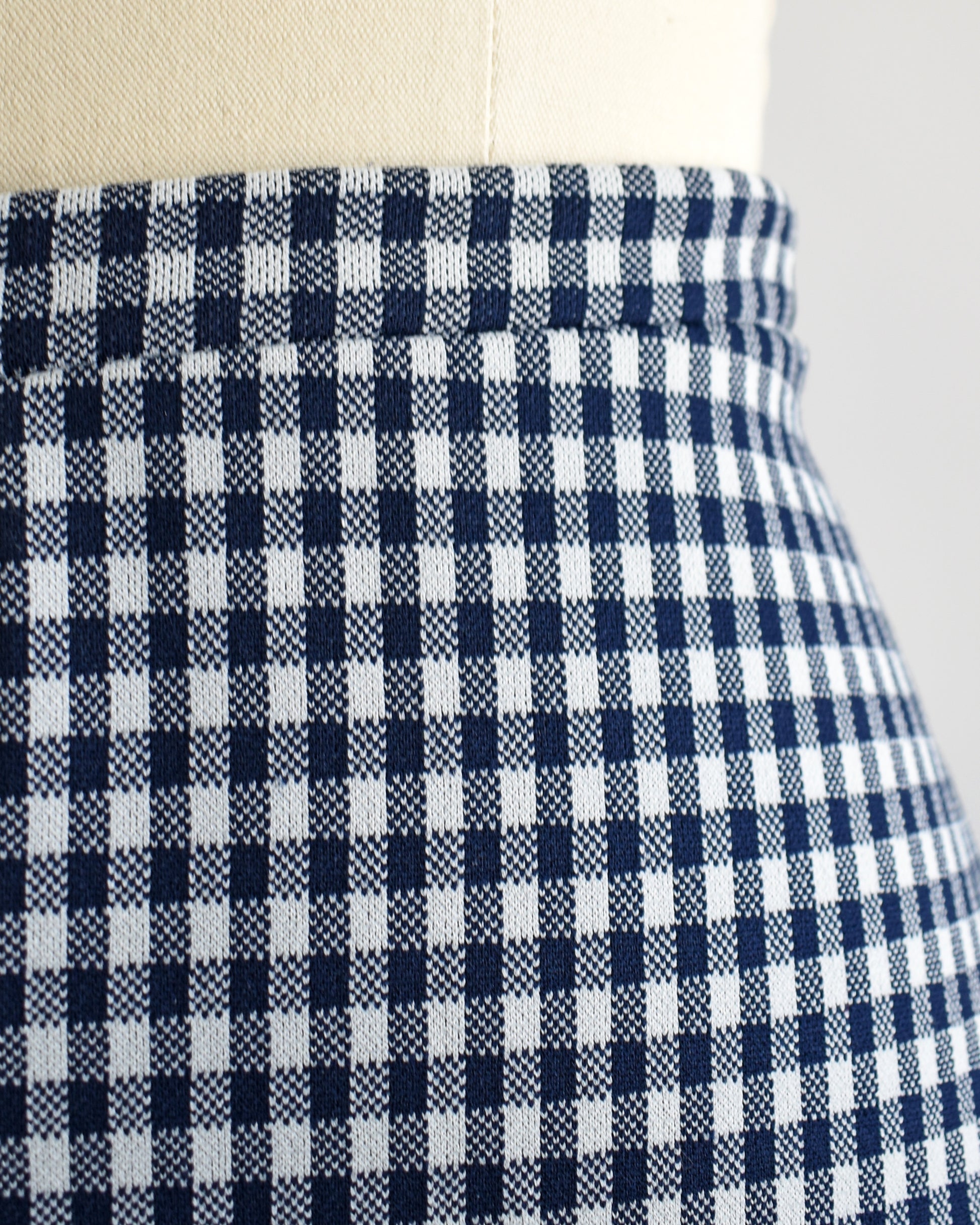 close up of the waistline of a pair of vintage 1970s blue and white gingham bell bottom pants on a dress form