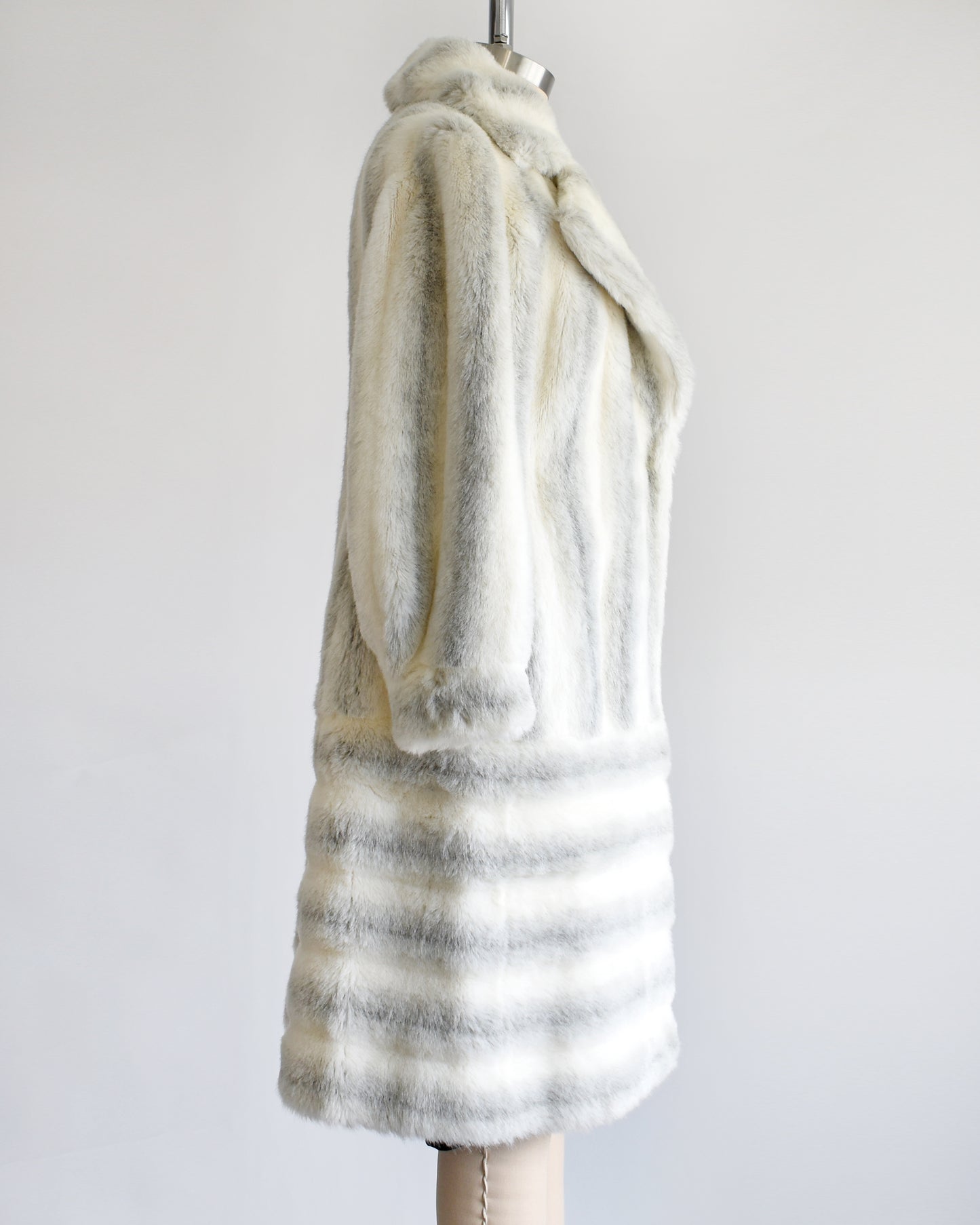 side view of a vintage 1970s white and gray striped faux fur coat on a dress form