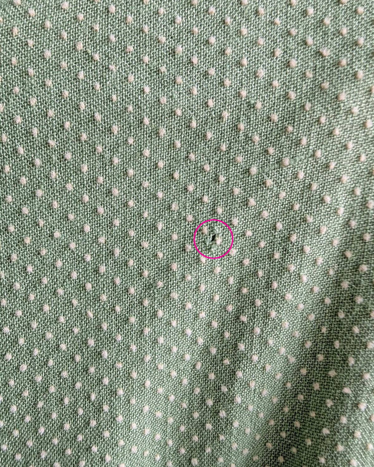 close up of the back of the right shoulder that has a small hole circled in pink