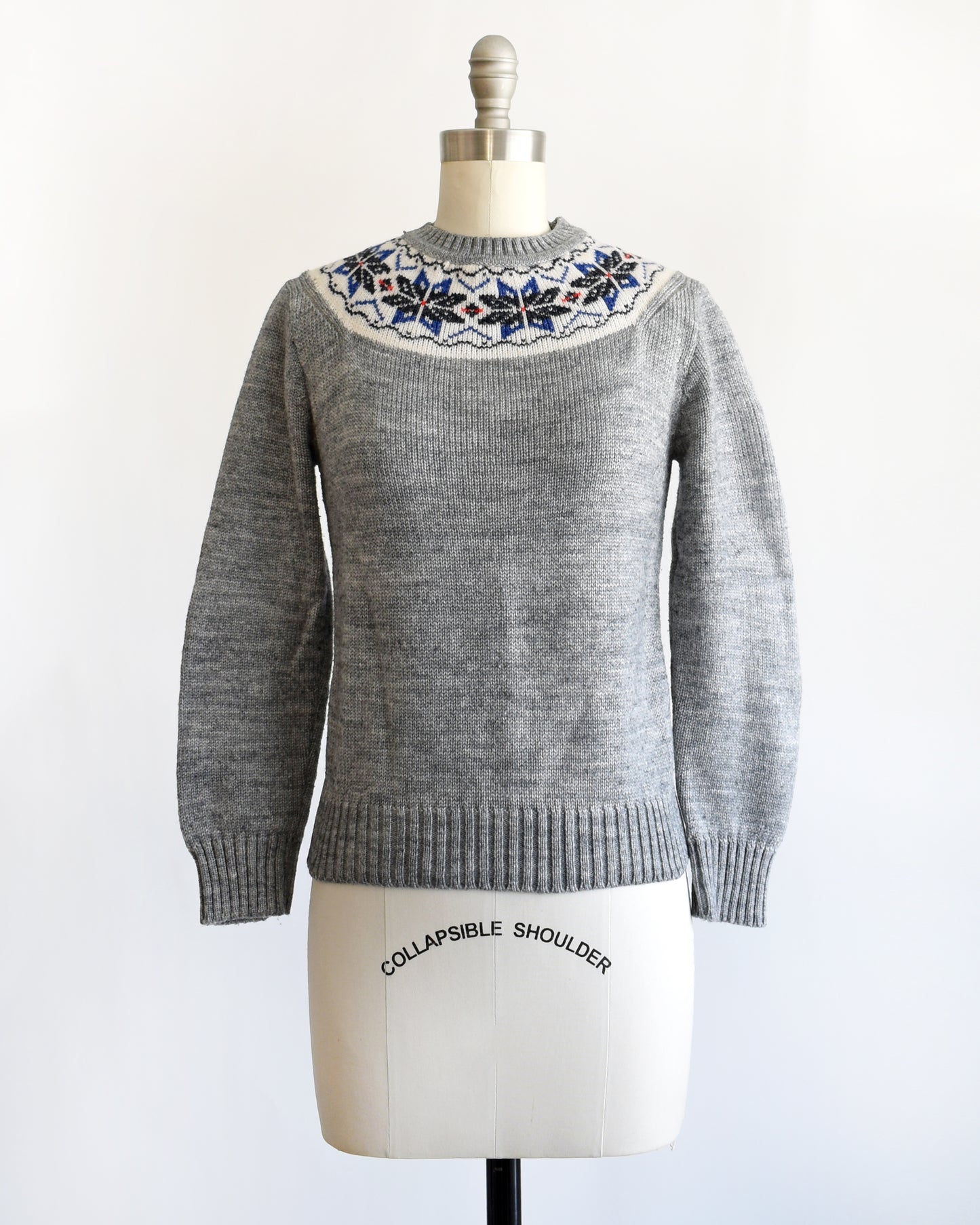 a vintage 1970s gray sweater with snowflake patterned neckline on a mannequin against a white background