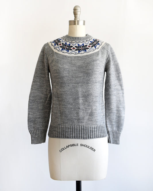 a vintage 1970s gray sweater with snowflake patterned neckline on a mannequin against a white background